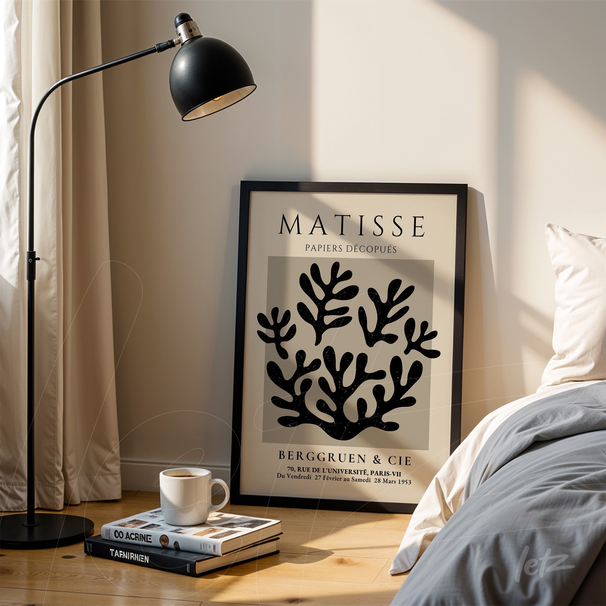 quadro decorativo com recortes de papel em preto sobre fundo claro, moldura preta, apoiado sobre chão de madeira ao lado de uma luminária de pé