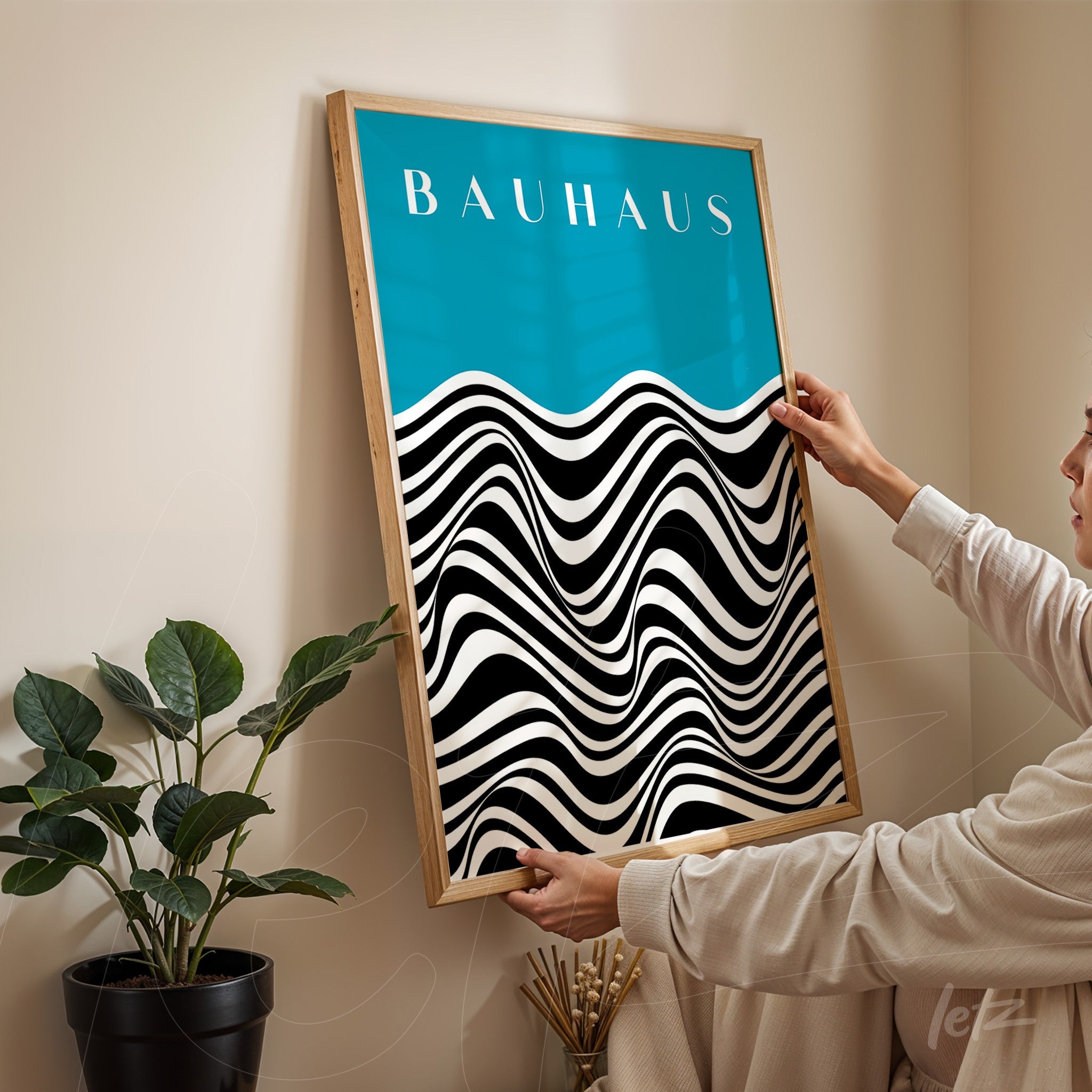 pôster com design ondulado em preto e branco sobre fundo azul com texto 'bauhaus', emoldurado em madeira clara exibido por pessoa