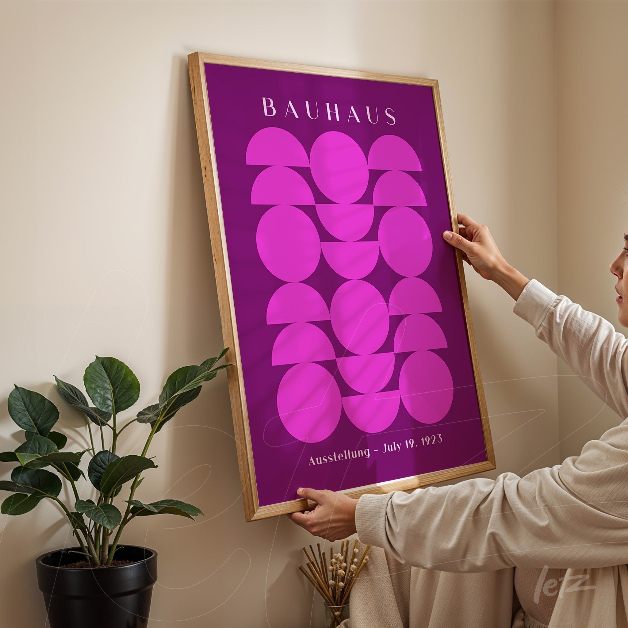 pôster impresso com arte geométrica em estilo bauhaus com moldura de madeira clara sendo segurado por uma pessoa