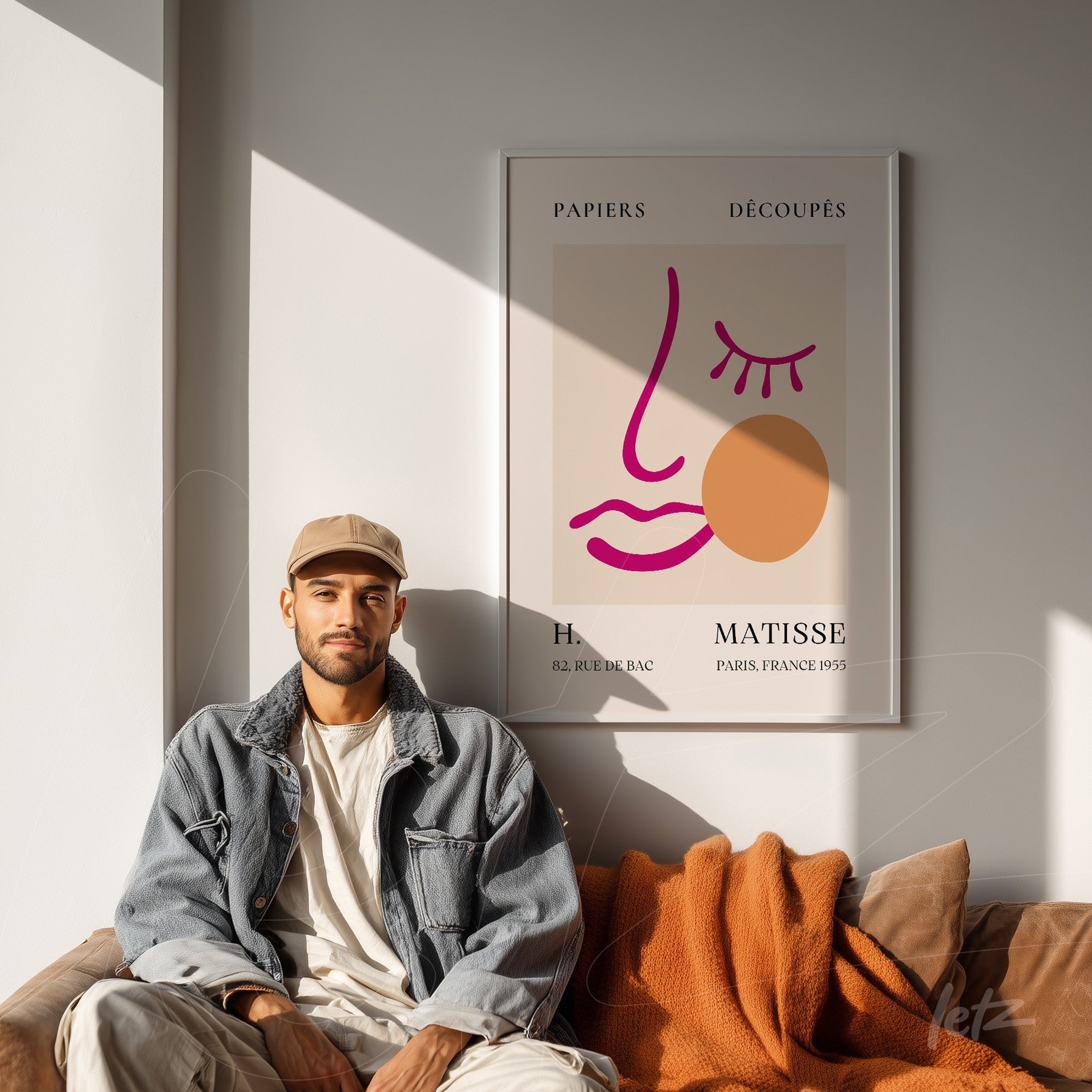 quadro decorativo em moldura clara com arte abstrata de rosto estilizado de Henri Matisse, exibido em parede iluminada ao lado de um homem sentado em sofá