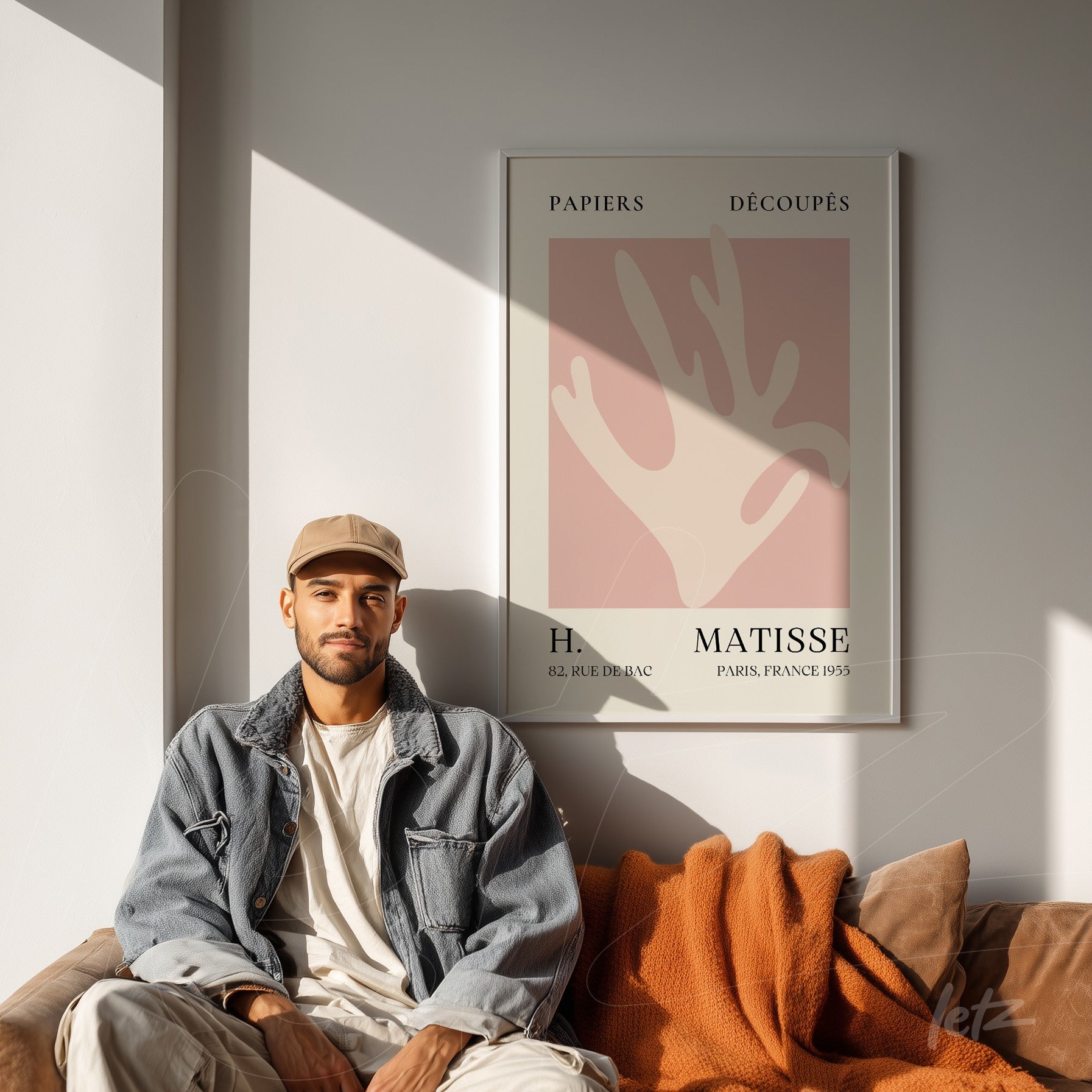 quadro decorativo de arte moderna com fundo rosa claro e formas abstratas, moldura branca, exposto em uma sala com sofá e luz natural