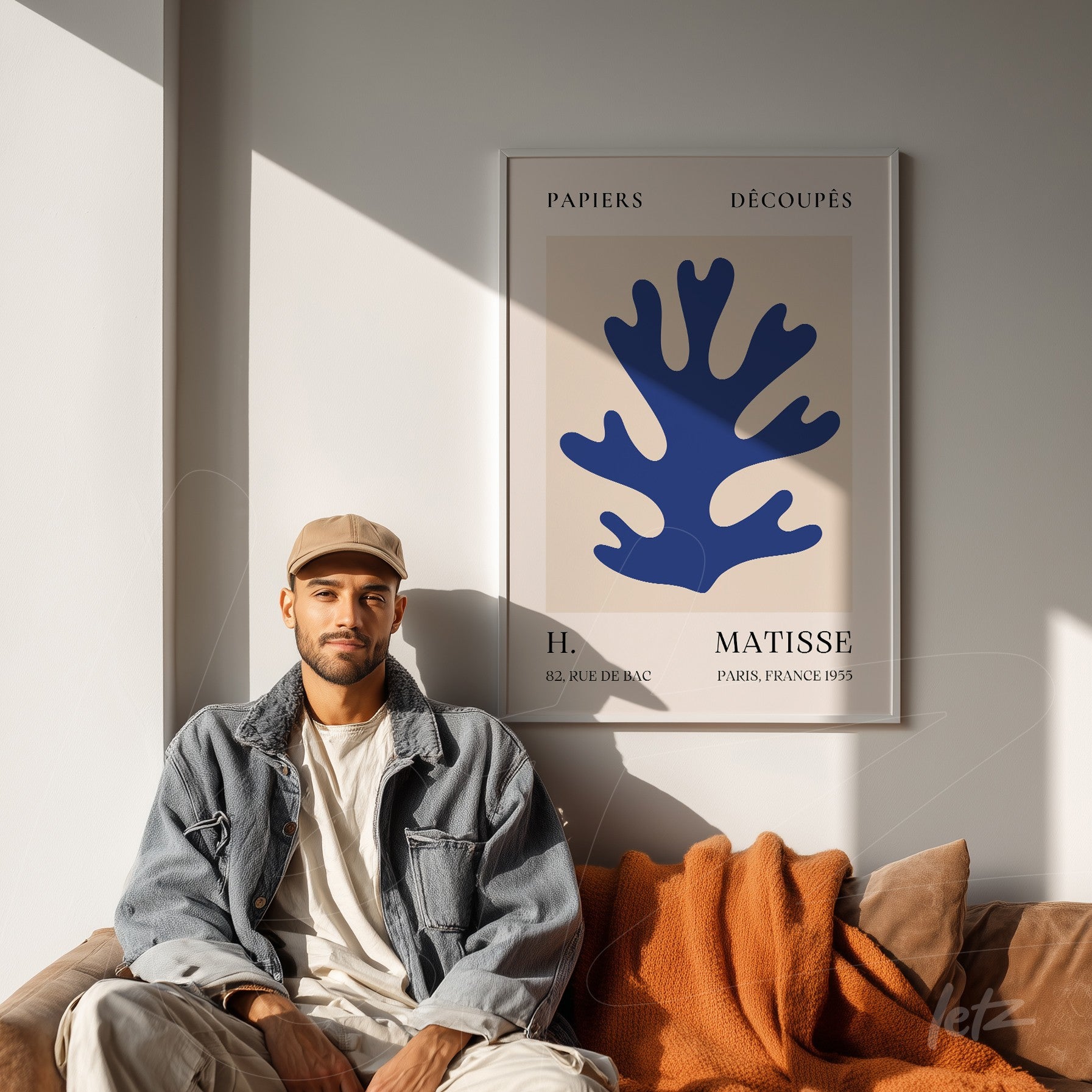 quadro com arte moderna emoldurada retratando uma forma de coral azul sobre fundo nude, exibido em um ambiente elegante com sofá de couro marrom