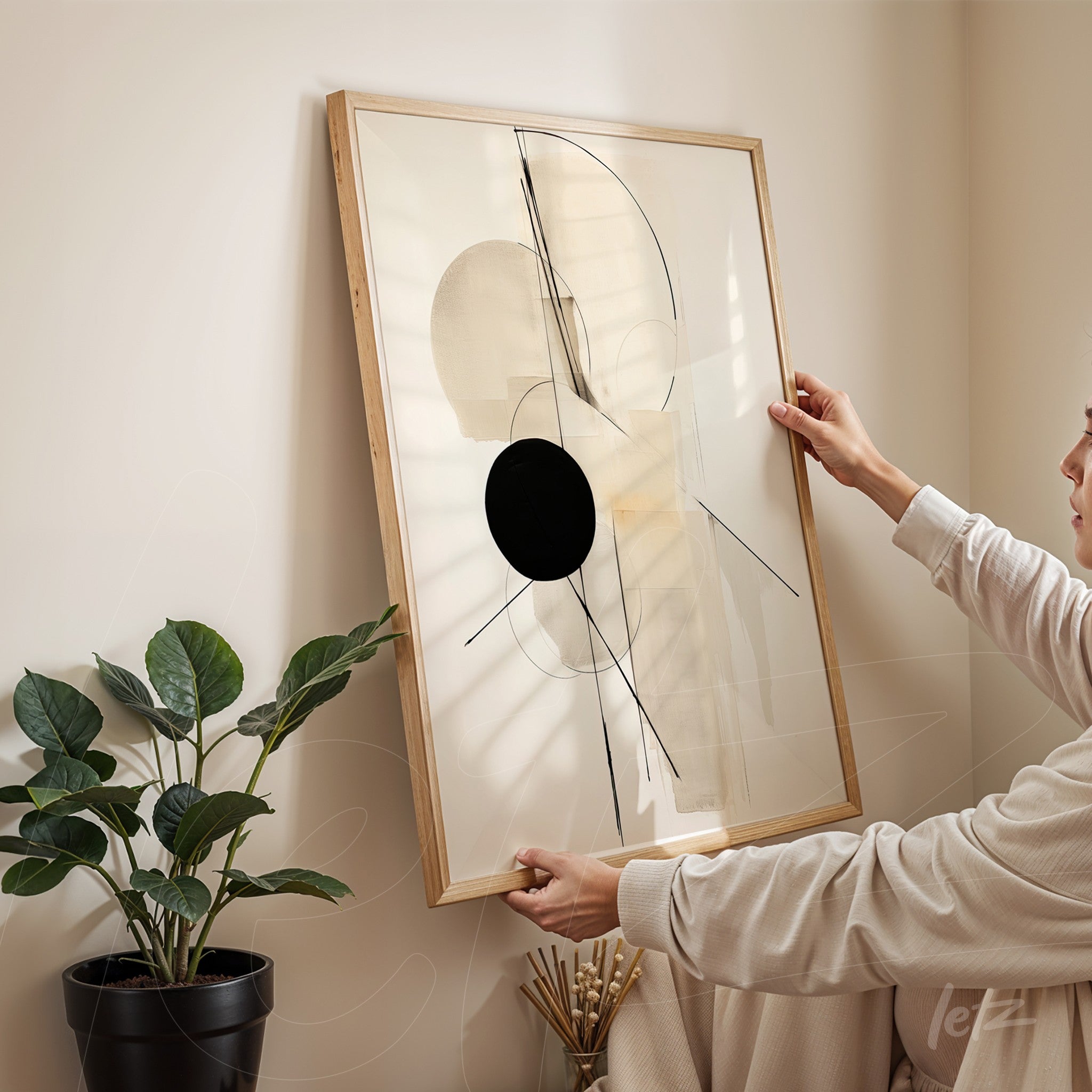 quadro moderno com composições geométricas em moldura de madeira clara, sendo segurado por uma pessoa em ambiente interno