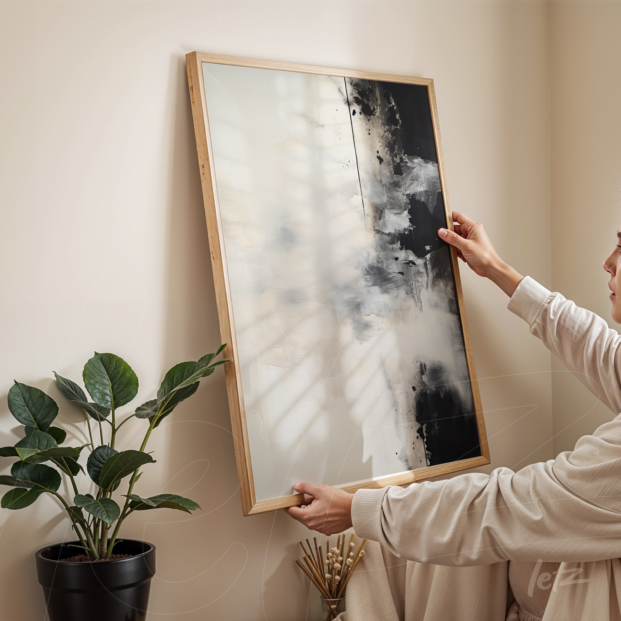quadro abstrato em moldura de madeira clara com predominância de preto e branco, apoiado em uma parede clara