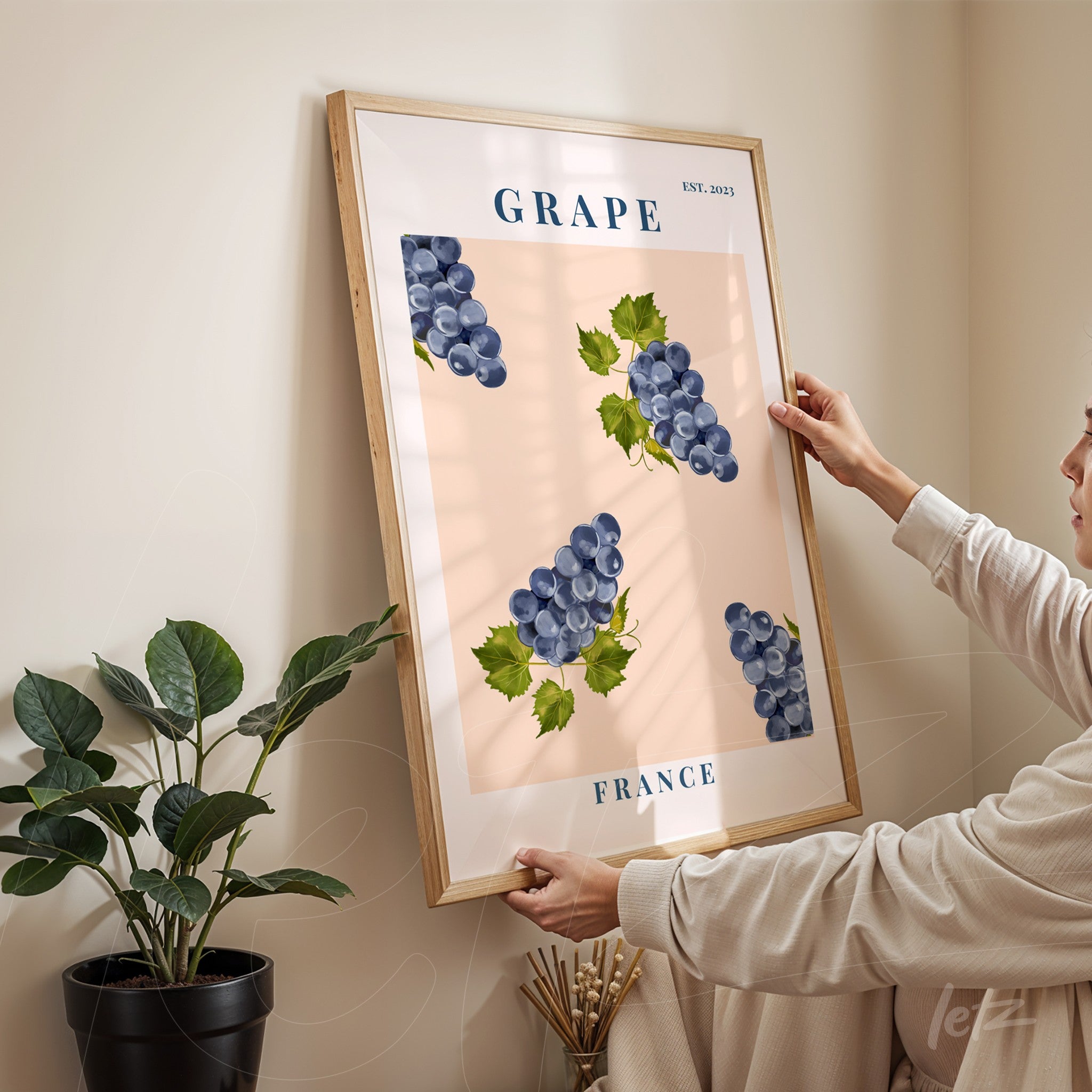 quadro com ilustrações de cachos de uvas azuis sobre fundo rosa, em moldura de madeira clara