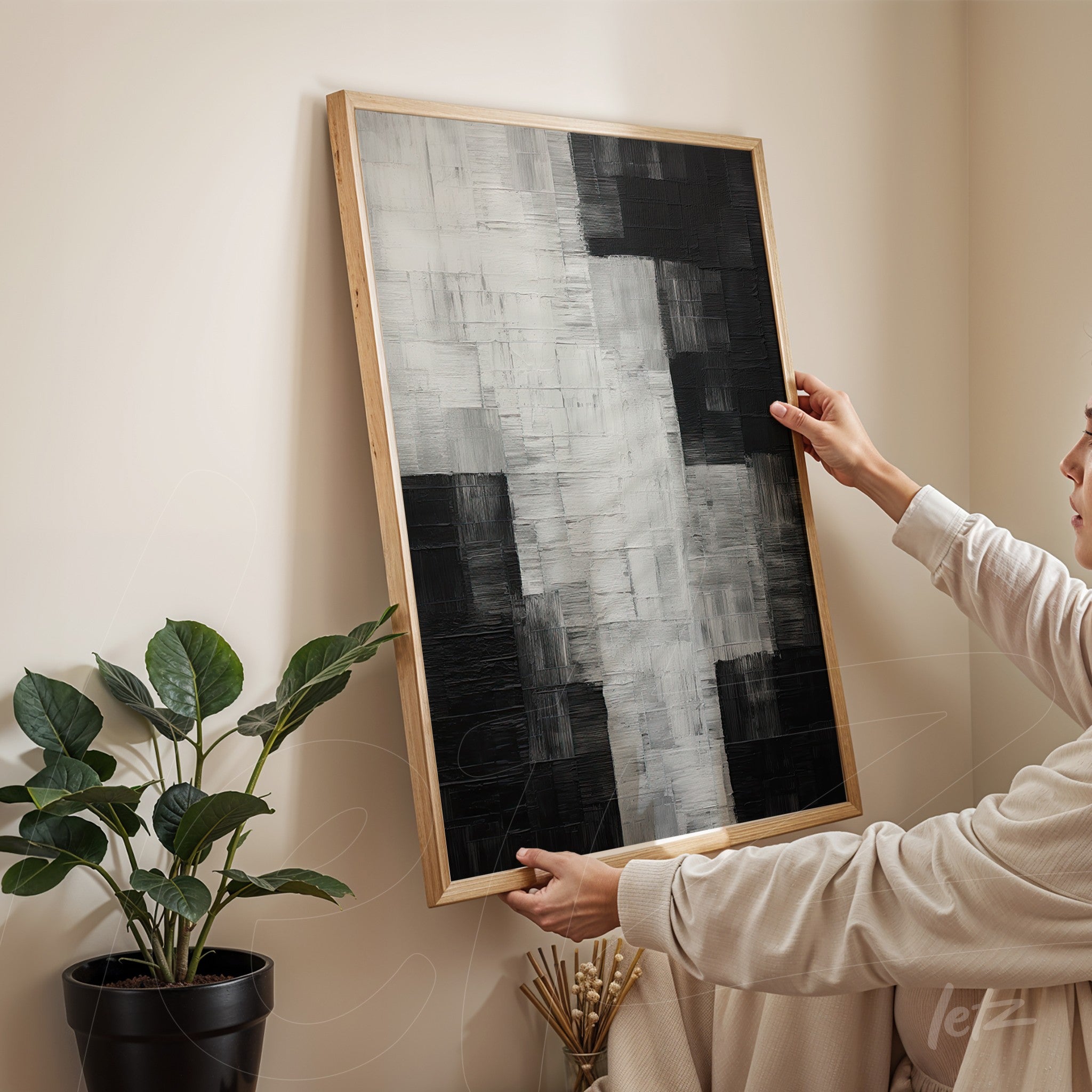 quadro abstrato em preto e branco com textura em relevo, moldura de madeira clara, exposto contra parede neutra