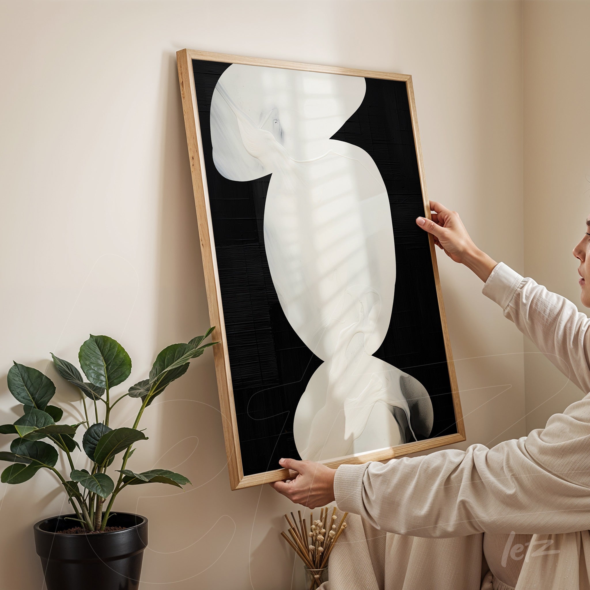 quadro com arte abstrata em tons de branco e preto, moldura de madeira clara exibido em ambiente aconchegante