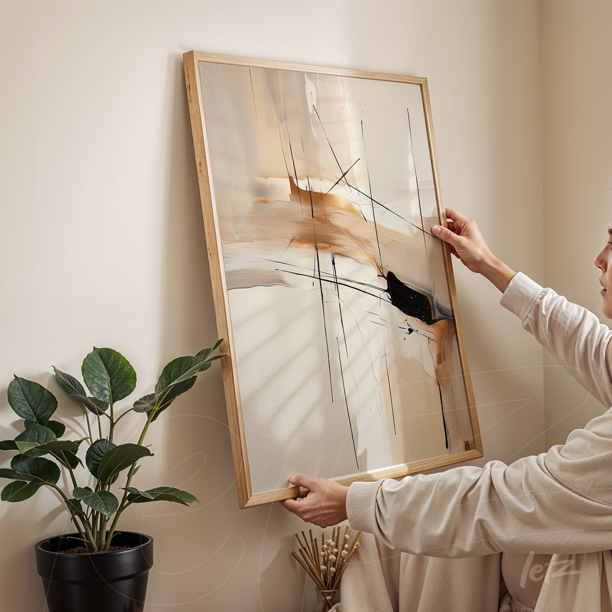 quadro abstrato em moldura de madeira clara, com traços em preto e tons neutros, apoiado na parede ao lado de planta