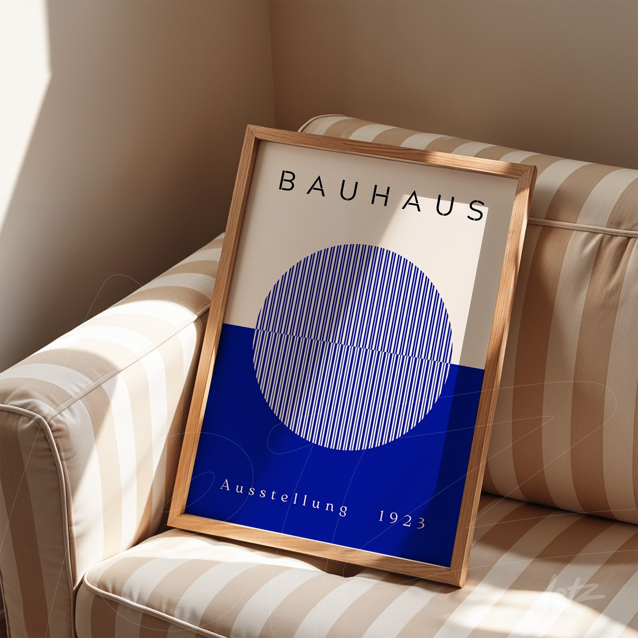 quadro com arte da bauhaus de círculo geométrico azul em moldura de madeira clara apoiado em sofá listrado