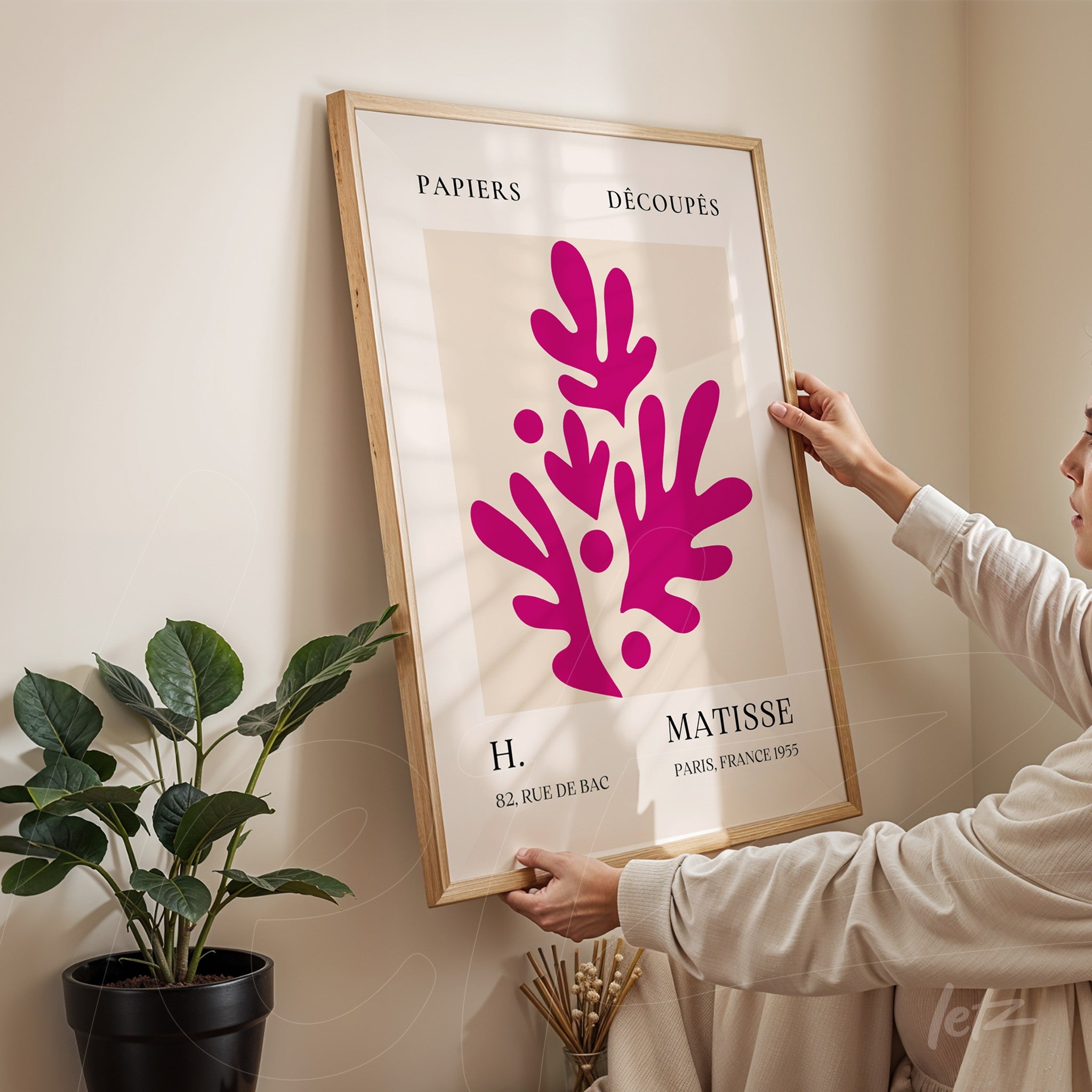 quadro com arte moderna em moldura de madeira clara, apresentando formas orgânicas em coloração rosa vibrante sobre fundo claro