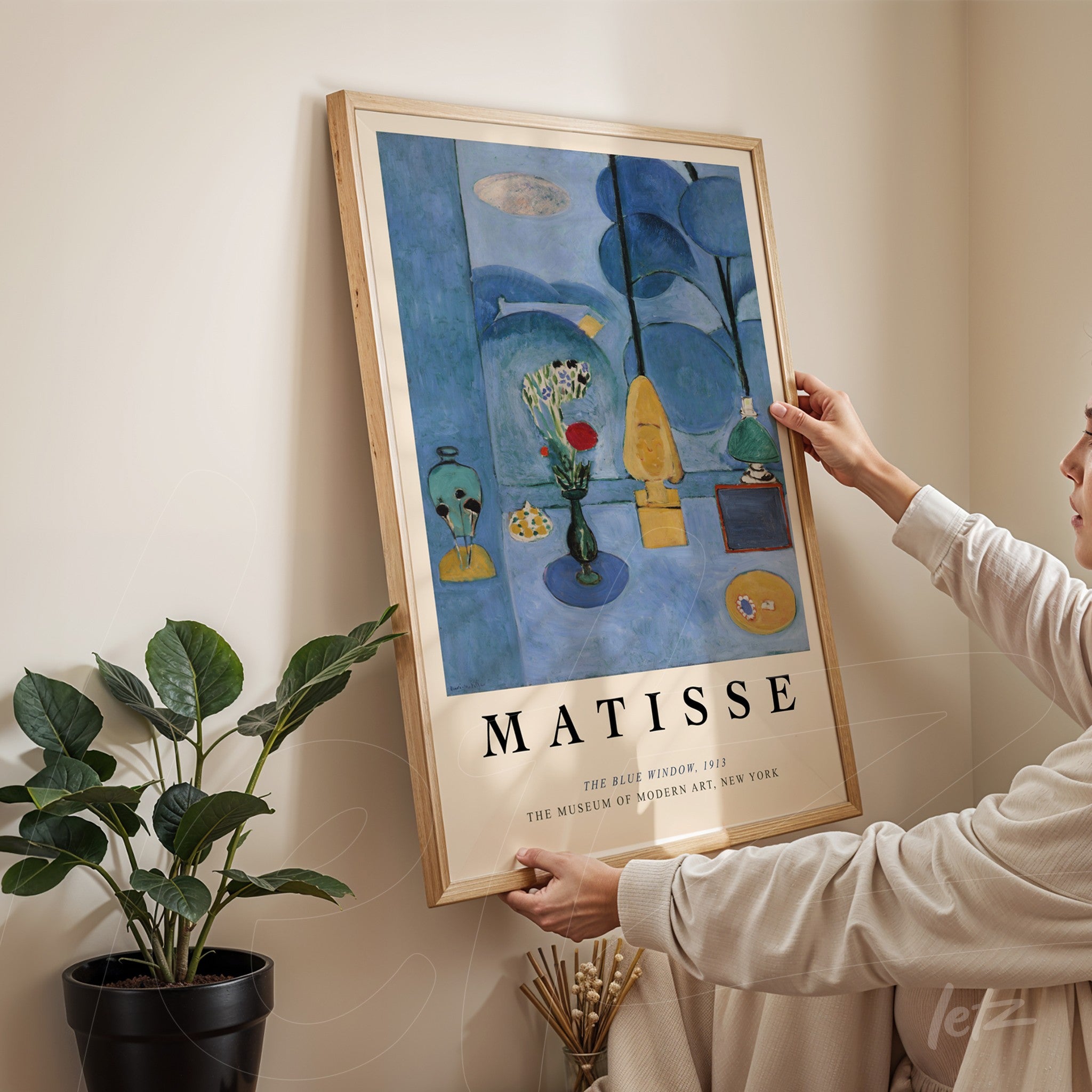 quadro com arte de Matisse, 'A Blue Period', em moldura de madeira clara, com fundo pastel e plantas ao redor