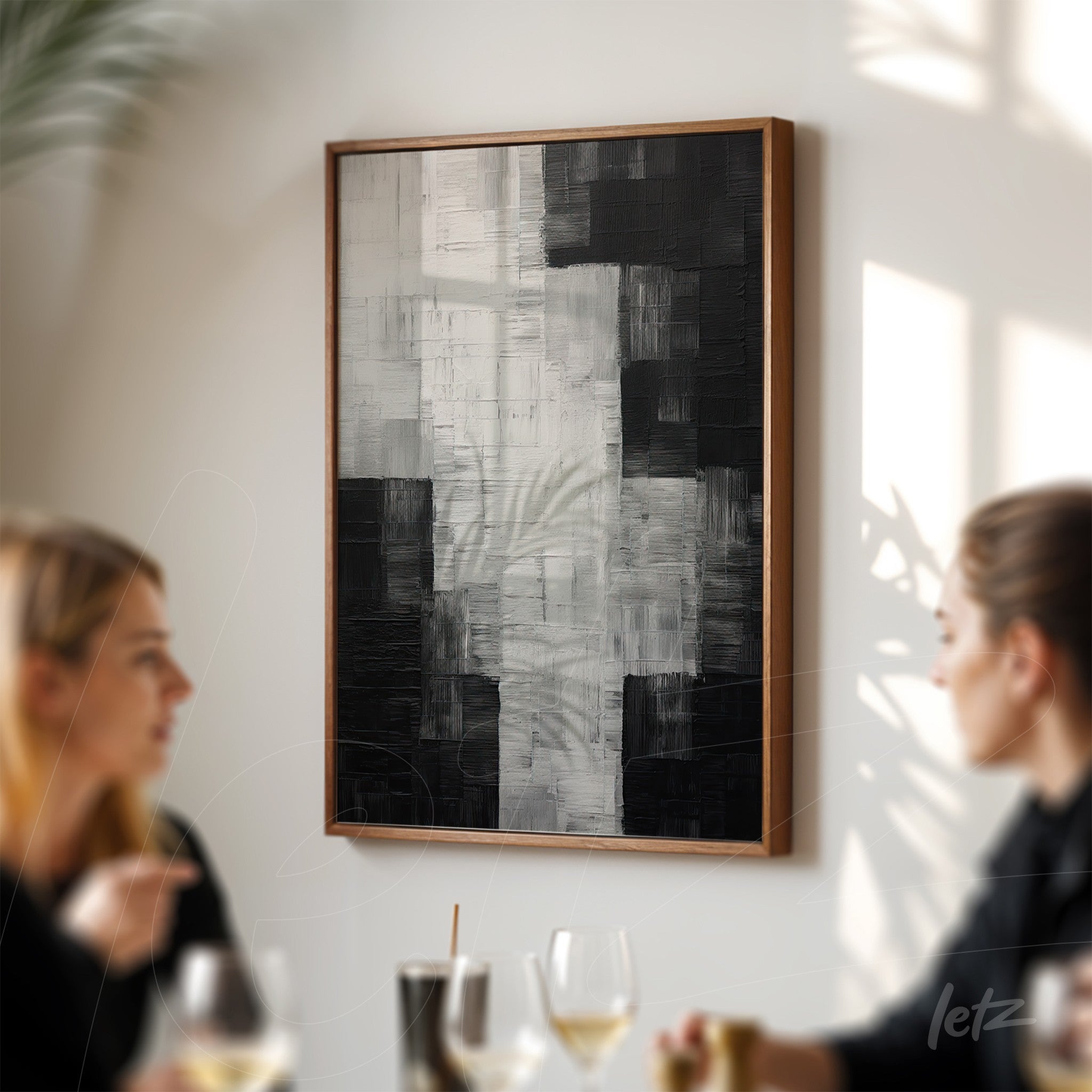 quadro abstrato em preto e branco com textura em relevo em moldura de madeira clara, exibido em ambiente de jantar