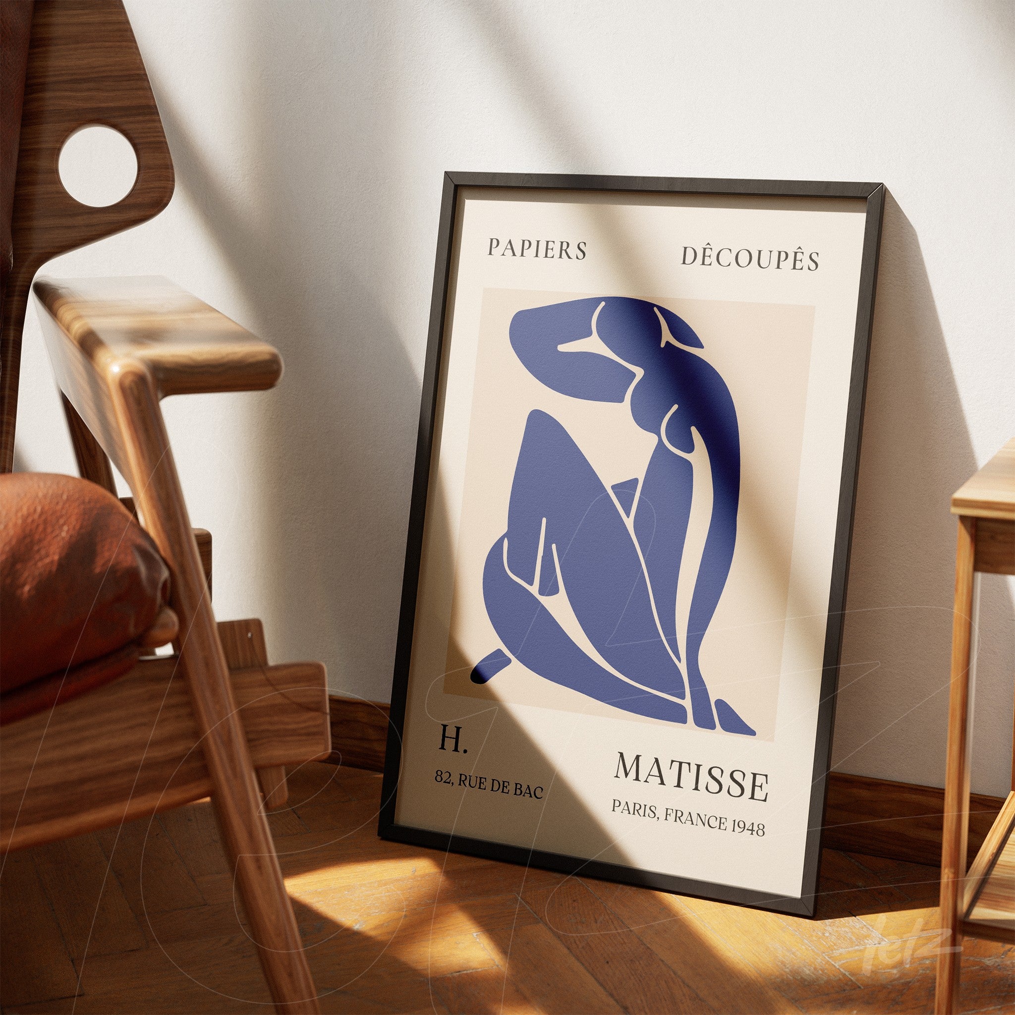 quadro com arte em estilo minimalista de figura feminina em azul, apoiado em parede clara ao lado de uma cadeira moderna