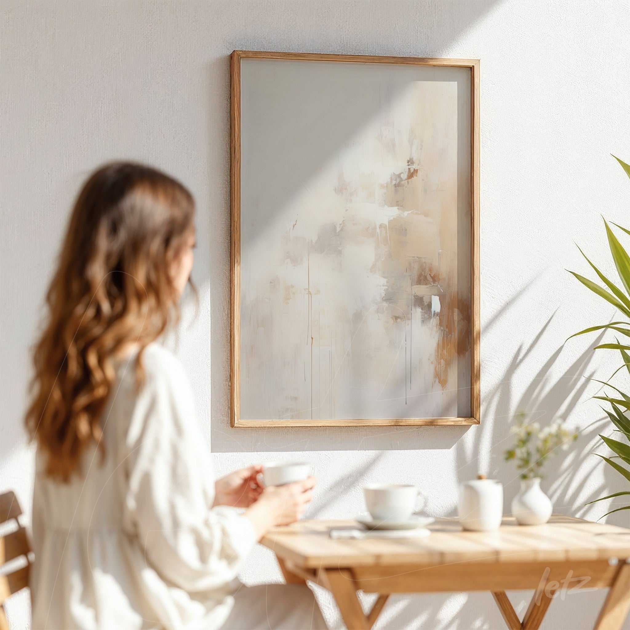 quadro com arte abstrata em tons de bege, exibido em moldura de madeira clara, decorando uma parede branca