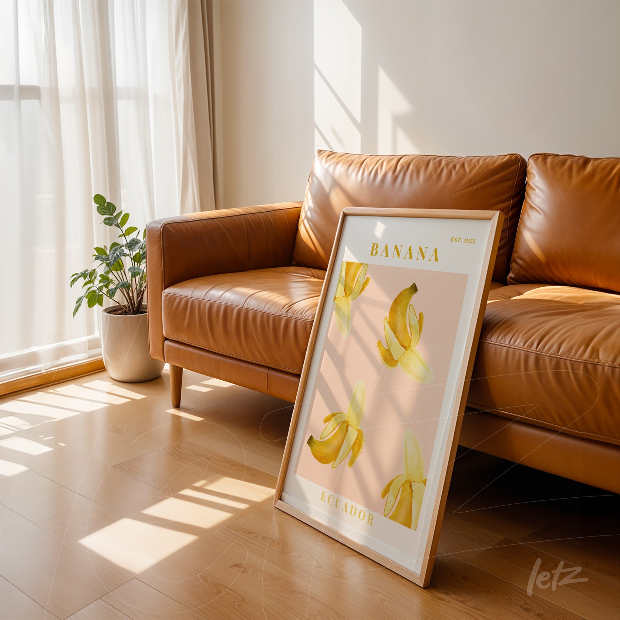 quadro emoldurado com arte de bananas em fundo rosa claro, apoiado ao lado de um sofá marrom em ambiente iluminado