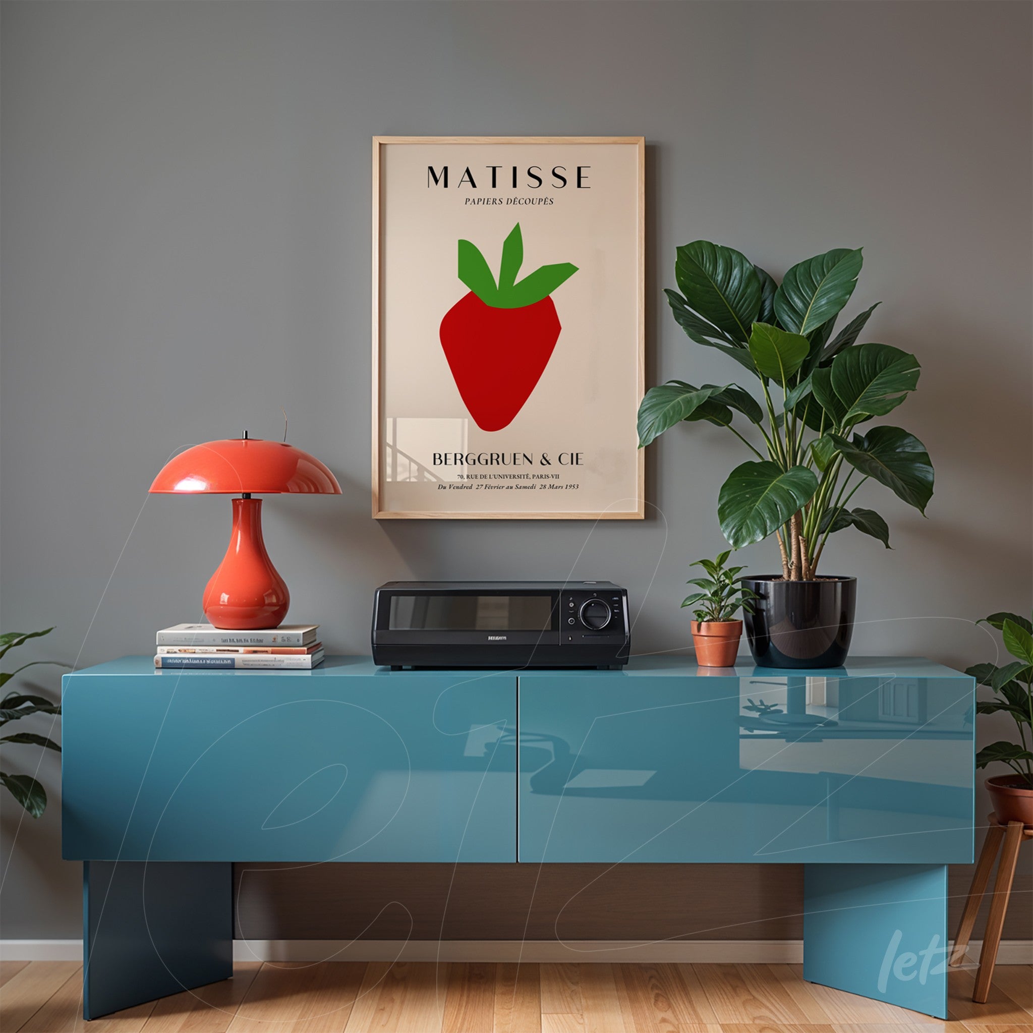 quadro com arte moderna de maça em moldura clara exposto sobre aparador azul com planta ao lado