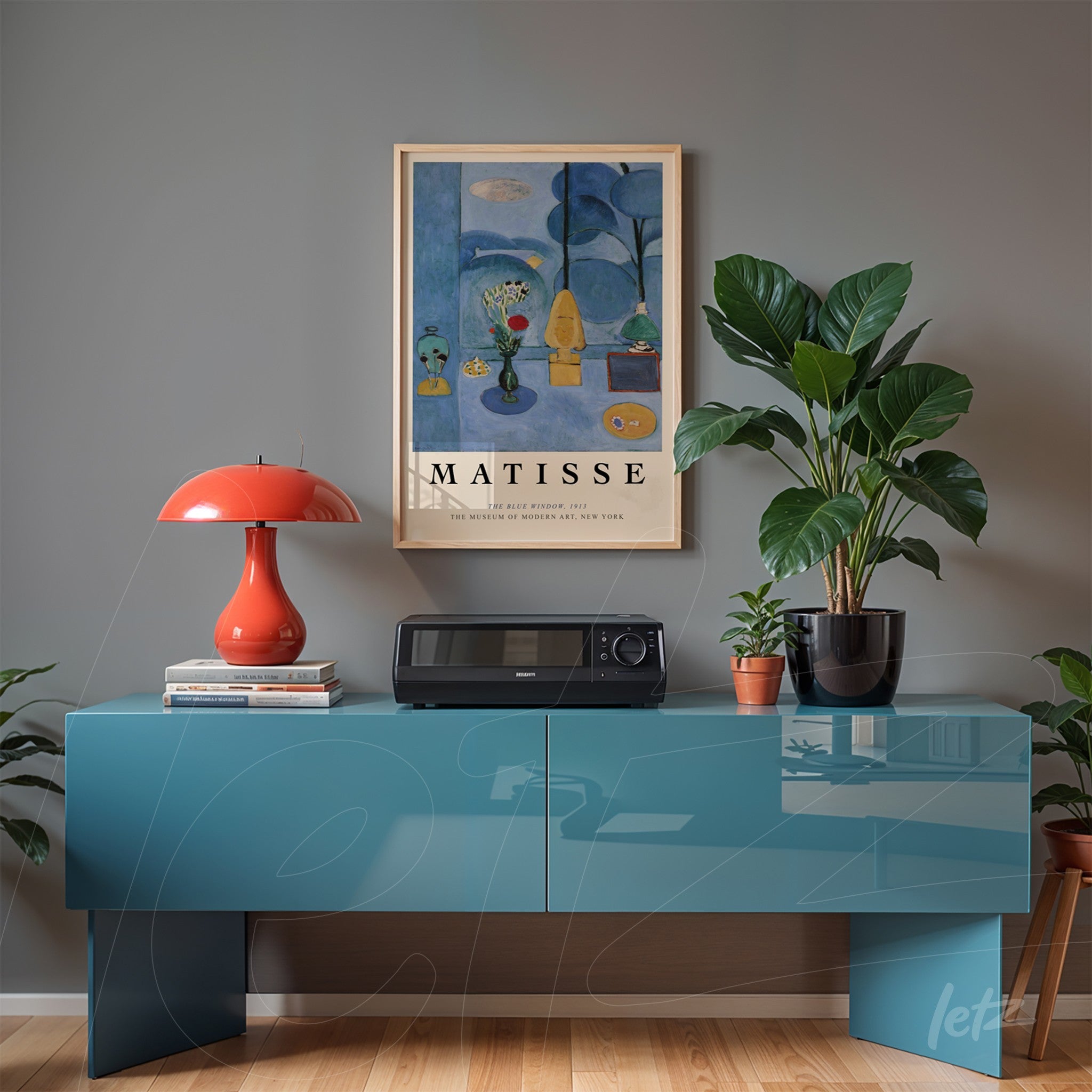 quadro emoldurado com arte de Henri Matisse sobre parede cinza, decorado com mesa azul e luminária vermelha