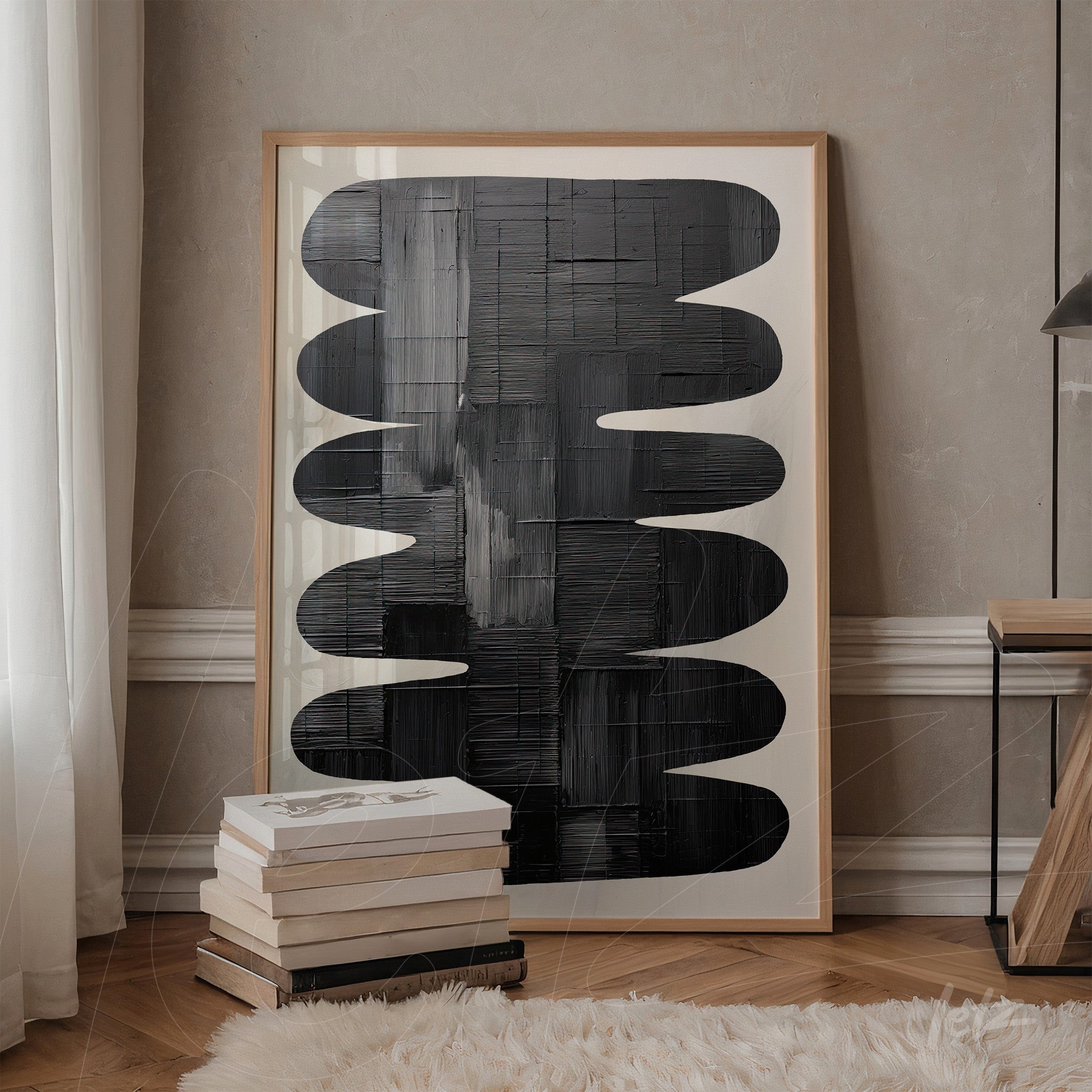 quadro em moldura clara com arte abstrata em preto e branco, exibido ao lado de pilha de livros sobre mesa de madeira