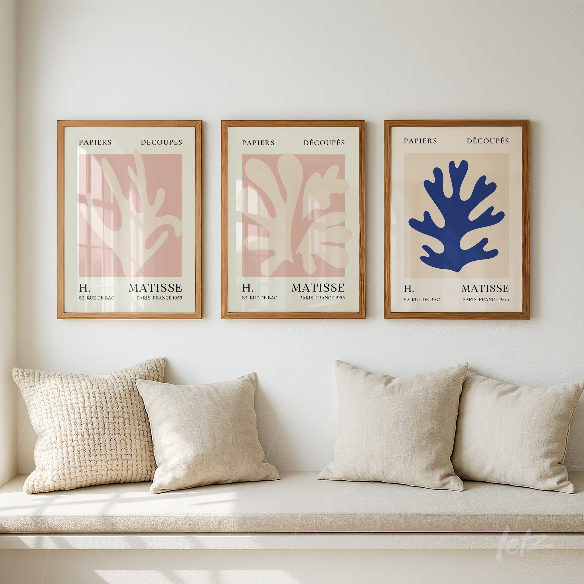 coleção de quadros decorativos com formas orgânicas em tons terrosos e azul, molduras de madeira clara, exibidos sobre parede branca