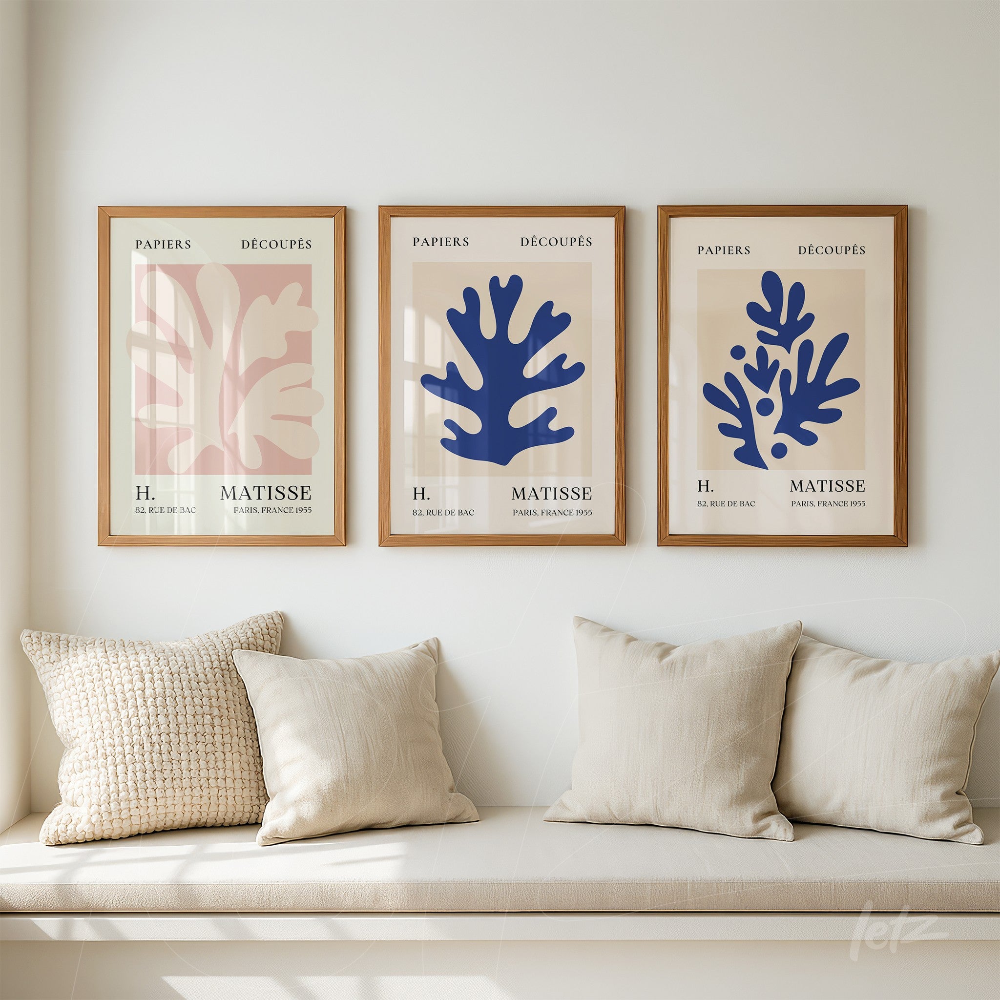 composição de quadros decorativos com ilustrações em estilo moderno de folhas em cores rosa e azul, moldurados em madeira clara sobre parede neutra