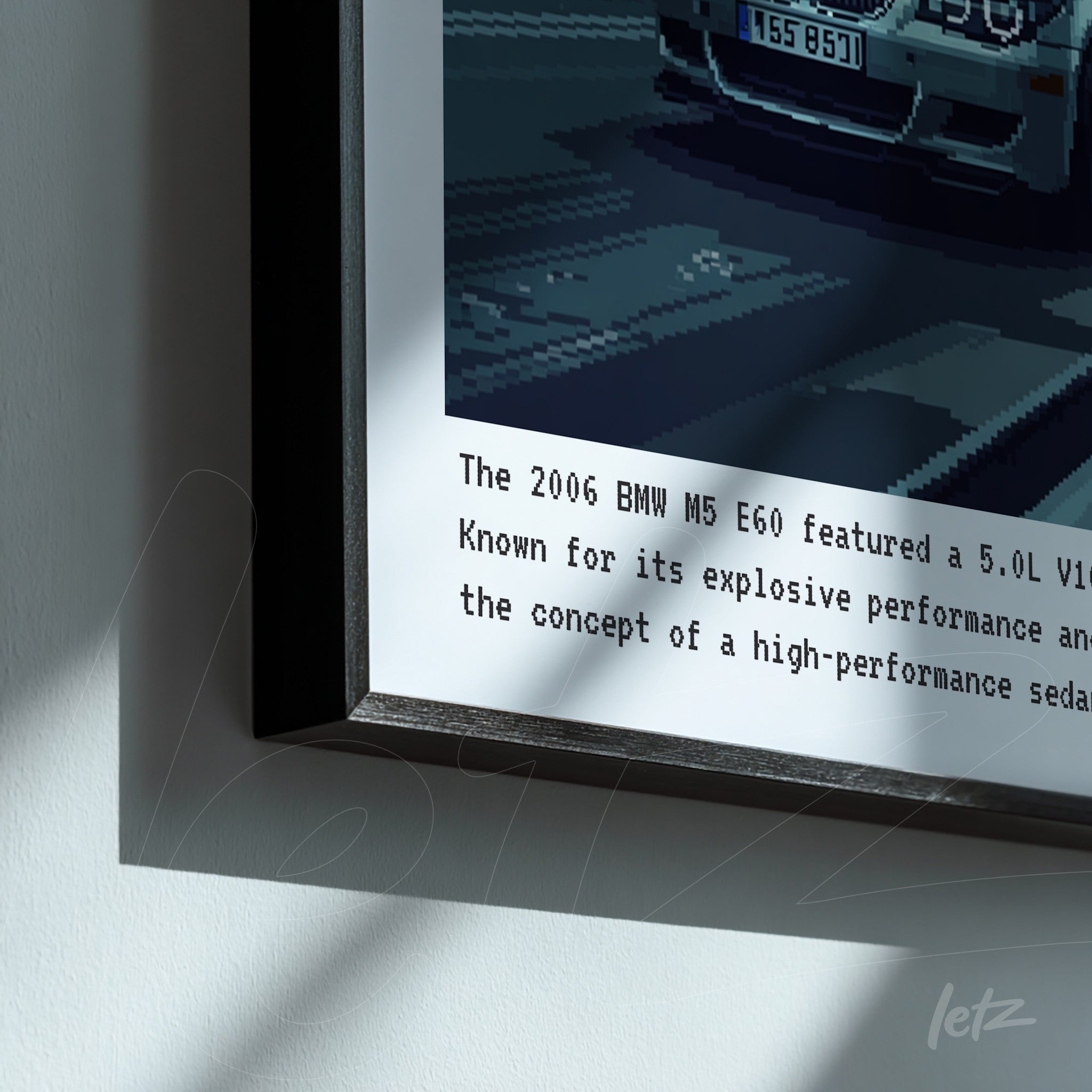 quadro com arte pixelada de um BMW M5 E60 em moldura preta, com texto informativo