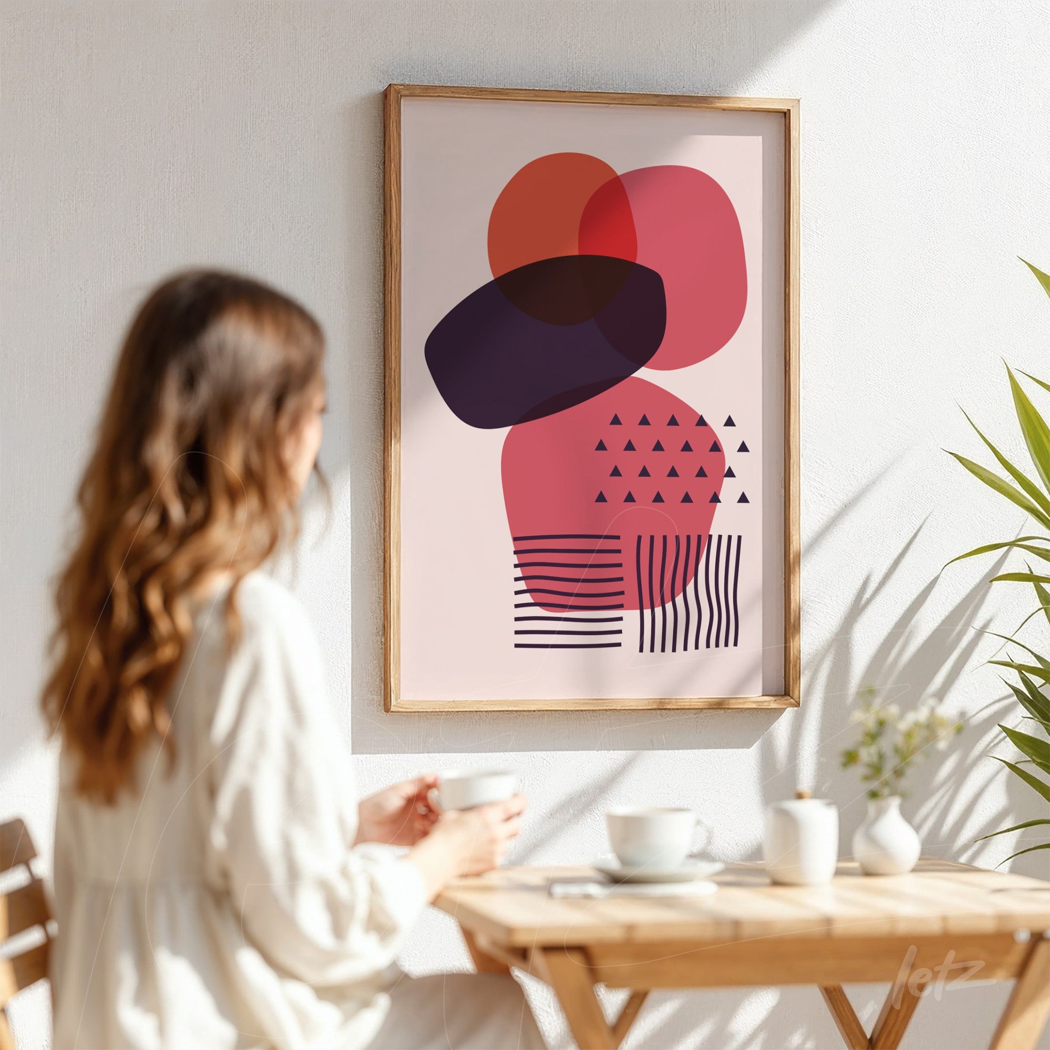 arte abstrata com formas geométricas em rosa e roxo emoldurada em madeira clara e exibida em parede branca