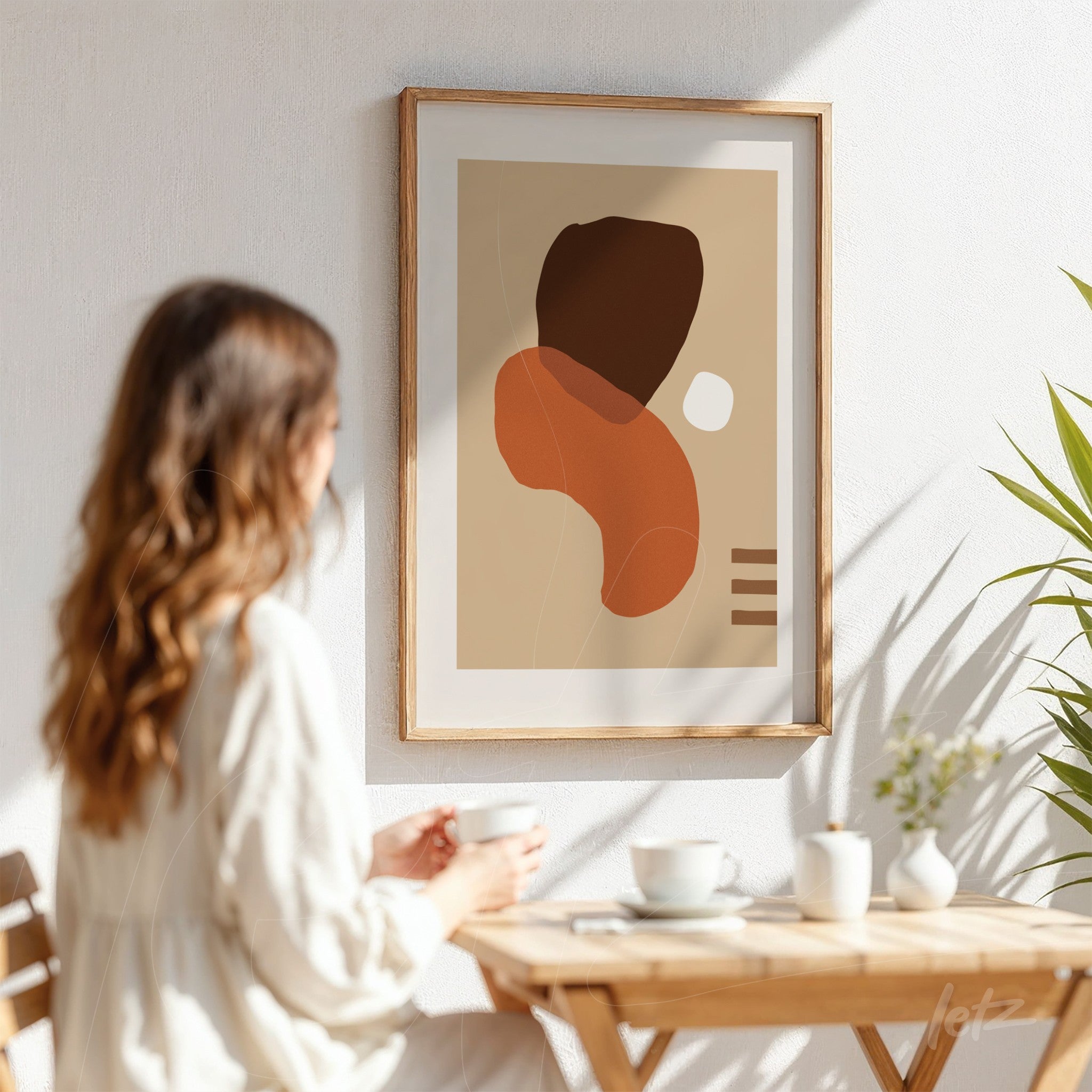 arte abstrata em cores terrosas com formas orgânicas e moldura de madeira em ambiente de café