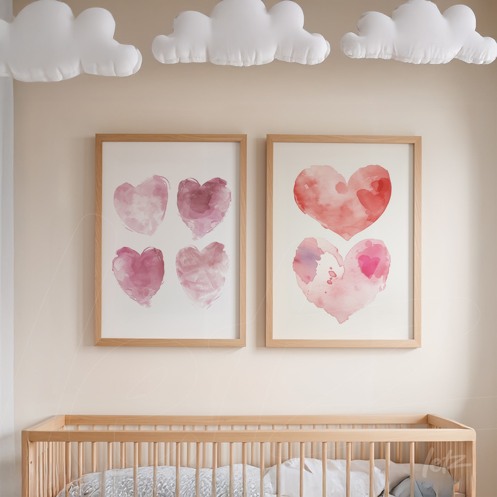dupla de quadros com ilustrações de corações em aquarela nas cores rosa, em molduras de madeira clara, exibidos sobre um berço de madeira sob nuvens decorativas