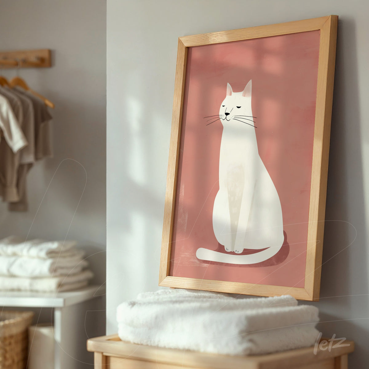 quadro com ilustração minimalista de um gato branco sobre fundo rosa, moldura de madeira clara, apoiado em um móvel em ambiente doméstico