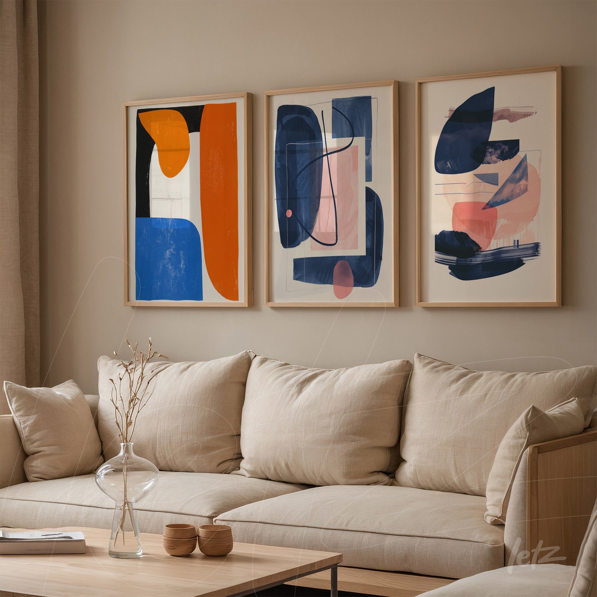 composição de três quadros abstratos em moldura de madeira clara sobre sofá de tecido bege
