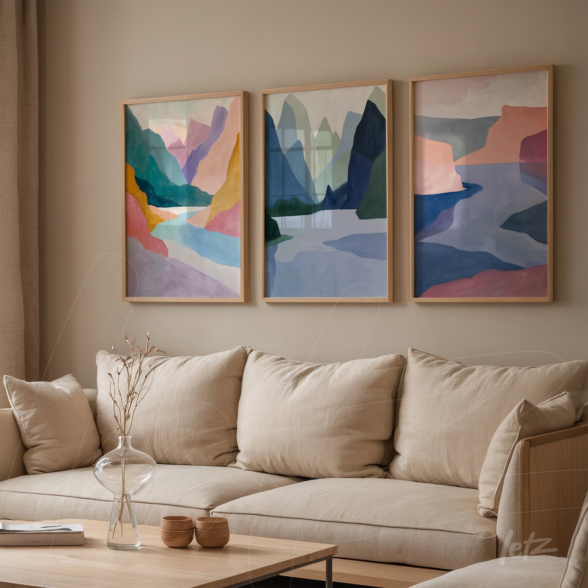 composição com três quadros de arte abstrata em moldura clara, exibindo montanhas e formas geométricas em tons suaves de azul, rosa e verde sobre parede de tom neutro