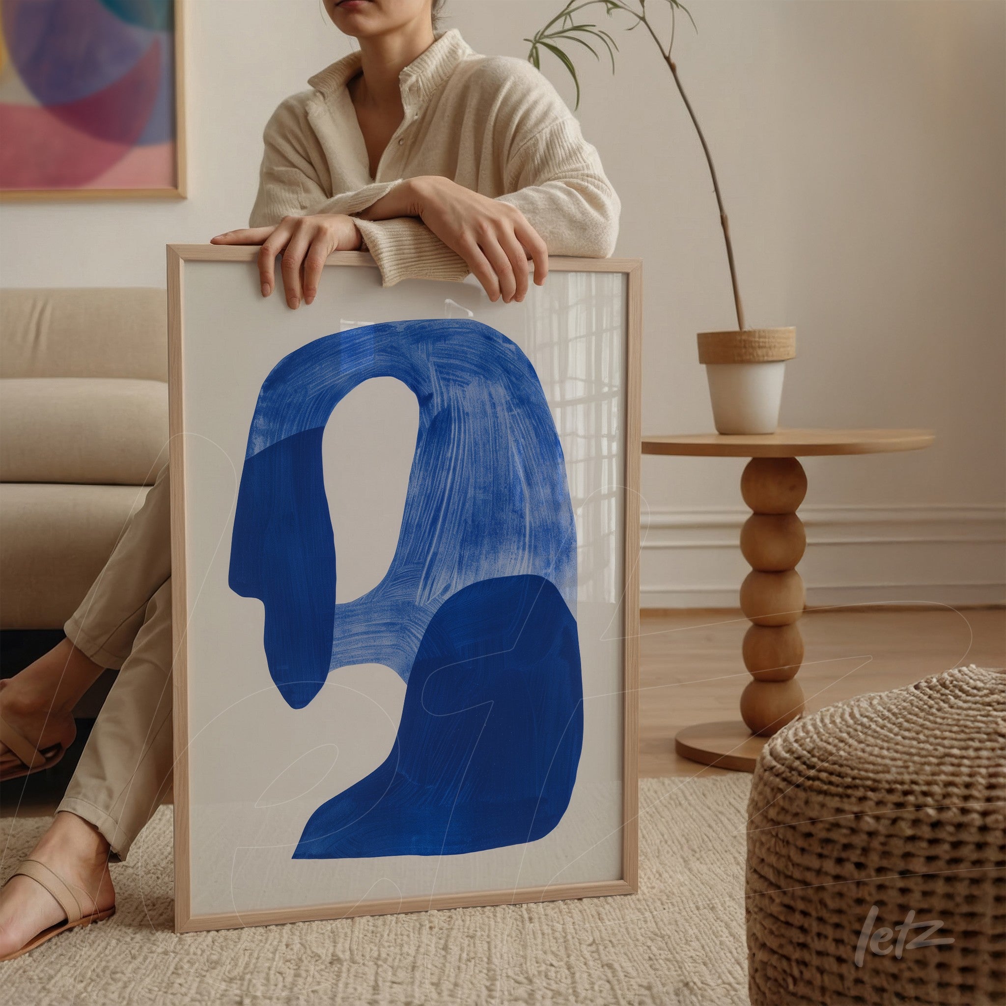 quadro com forma abstrata em azul marinho e fundo claro, moldura de madeira clara com detalhe de ambiente minimalista