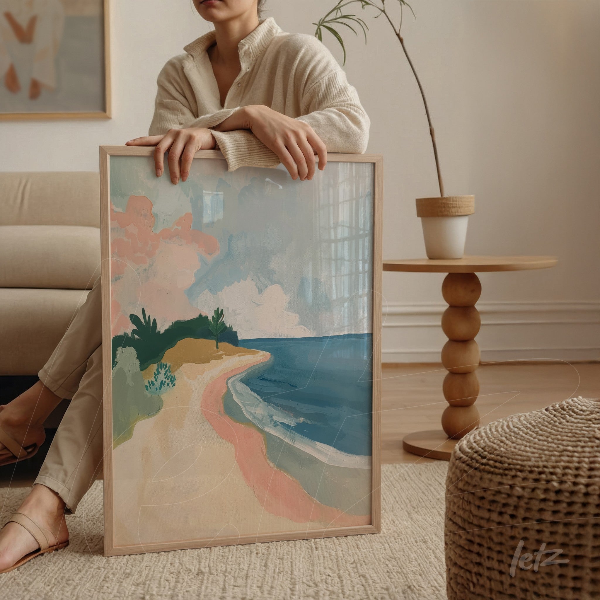 quadro em moldura clara com uma paisagem praiana em estilo abstrato, mostrando areia, mar e vegetação com cores suaves