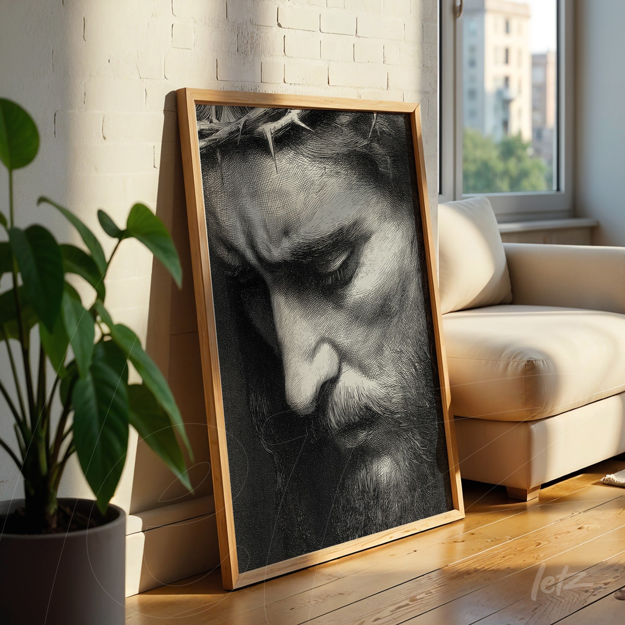 quadro com retrato em preto e branco de Cristo com expressão contemplativa em moldura de madeira clara, apoiado em um sofá