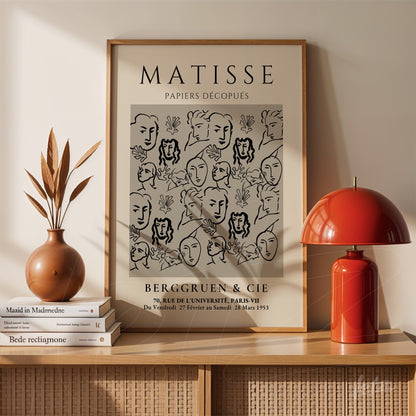 quadro decorativo com arte moderna de Matisse em moldura clara, destacando rostos estilizados sobre fundo com elementos florais