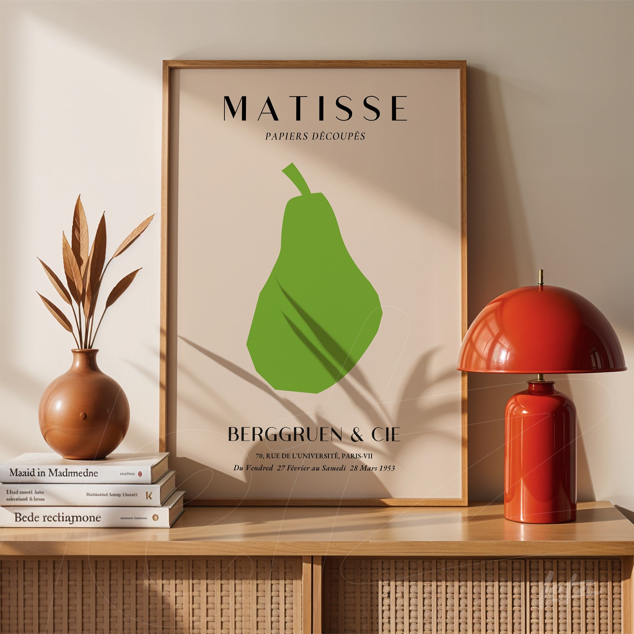 quadro decorativo com arte moderna de uma pêra em verde, moldura simples em madeira clara e fundo bege, exibido sobre uma prateleira com vasos e livros