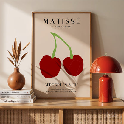 quadro com arte moderna de duas cerejas vermelhas com fundo claro e moldura clássica, exibido em mesa com decoração minimalista