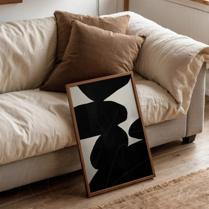 quadro com arte abstrata em tons de preto e branco, apoiado em sofá bege com almofadas marrons