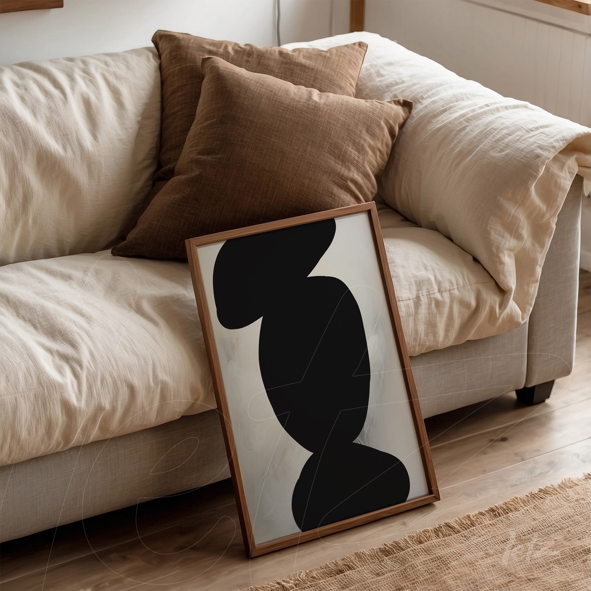 quadro minimalista com formas abstratas em preto, apoiado em sofá com almofadas marrons
