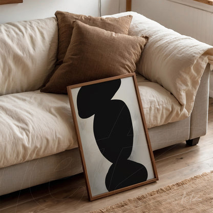 quadro minimalista com formas abstratas em preto, apoiado em sofá com almofadas marrons