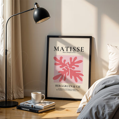 quadro emoldurado com arte abstrata de folhas rosa em destaque, título 'MATISSE' com detalhes em tipografia moderna, exibido ao lado de uma lâmpada de pé sobre parede clara