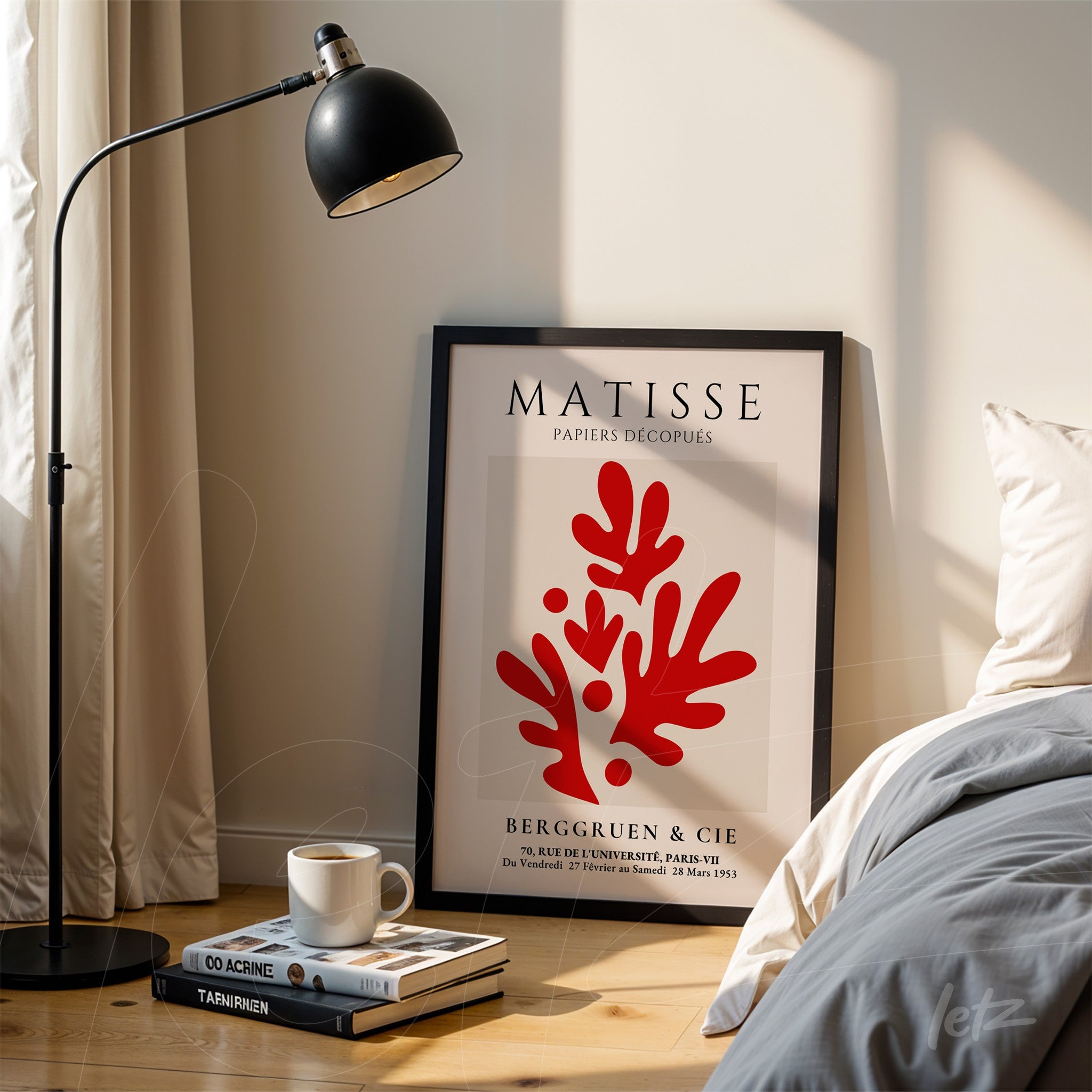 quadro com arte de Matisse em moldura preta com fundo claro e detalhes vermelhos de coral, apoiado ao lado de uma luminária e pilhas de livros