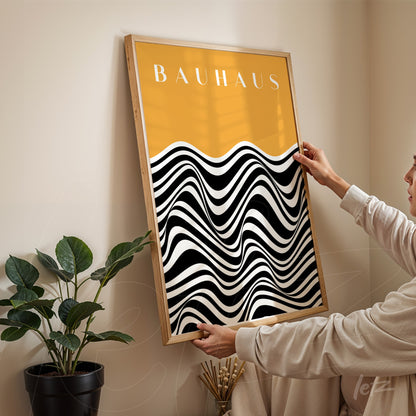 quadro com arte geométrica em preto e branco sob fundo amarelo, moldura de madeira clara, exibido em parede clara