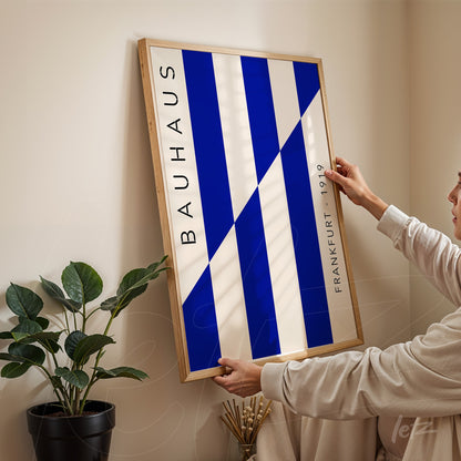 quadro emoldurado com design geométrico azul e branco inspirado em bauhaus, apoiado em parede de canto