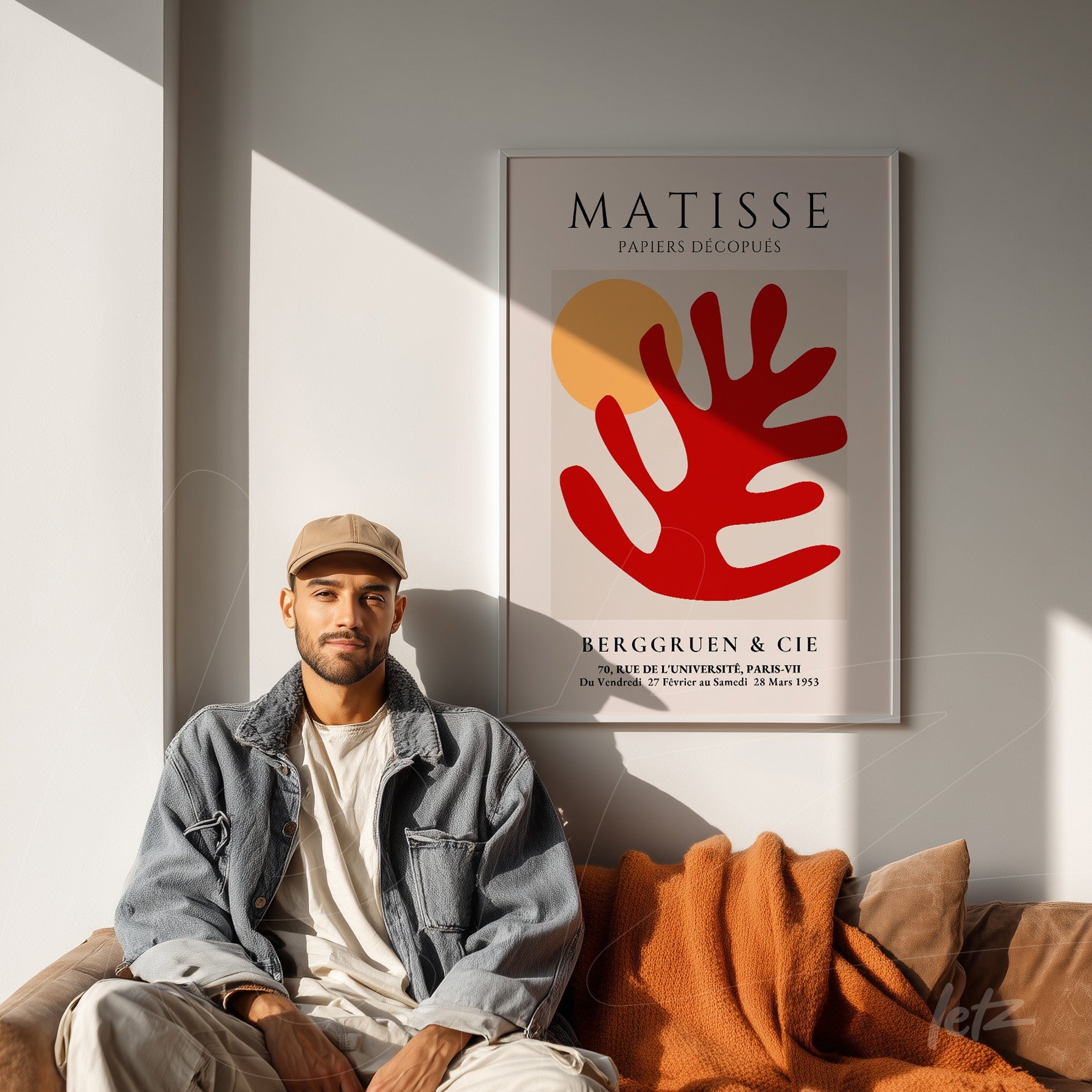 quadro com arte de Matisse apresentando formas abstratas em vermelho e amarelo, emoldurado com moldura branca, exibido acima de sofá com cobertor laranja