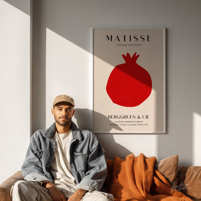 quadro decorativo com a arte de Matisse em tonalidade vermelha, apoiado em parede clara, com uma composição minimalista que destaca um romã