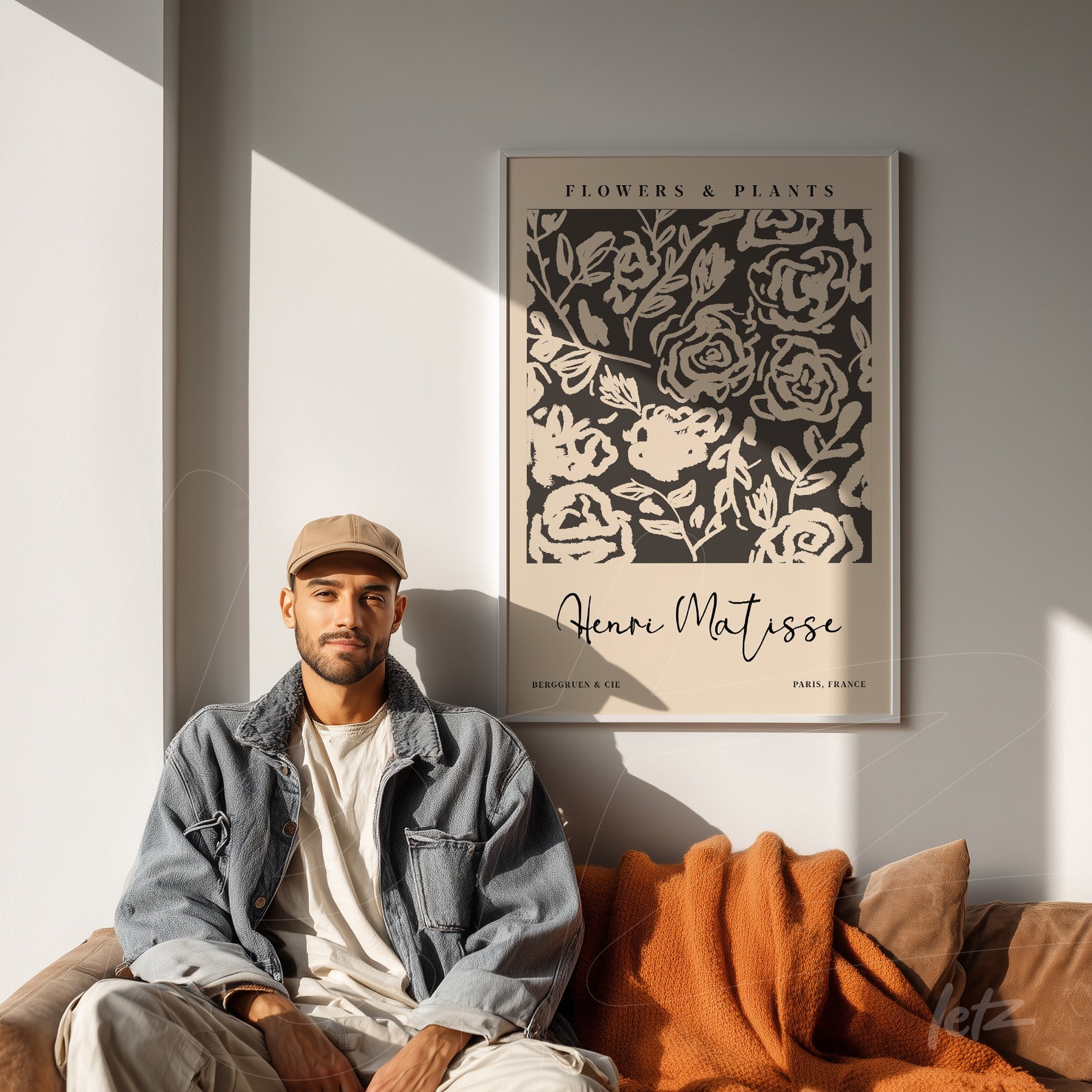 quadro decorativo com design de flores e plantas em moldura clássica, exibido sobre parede clara na sala com sofá marrom e cobertor laranja