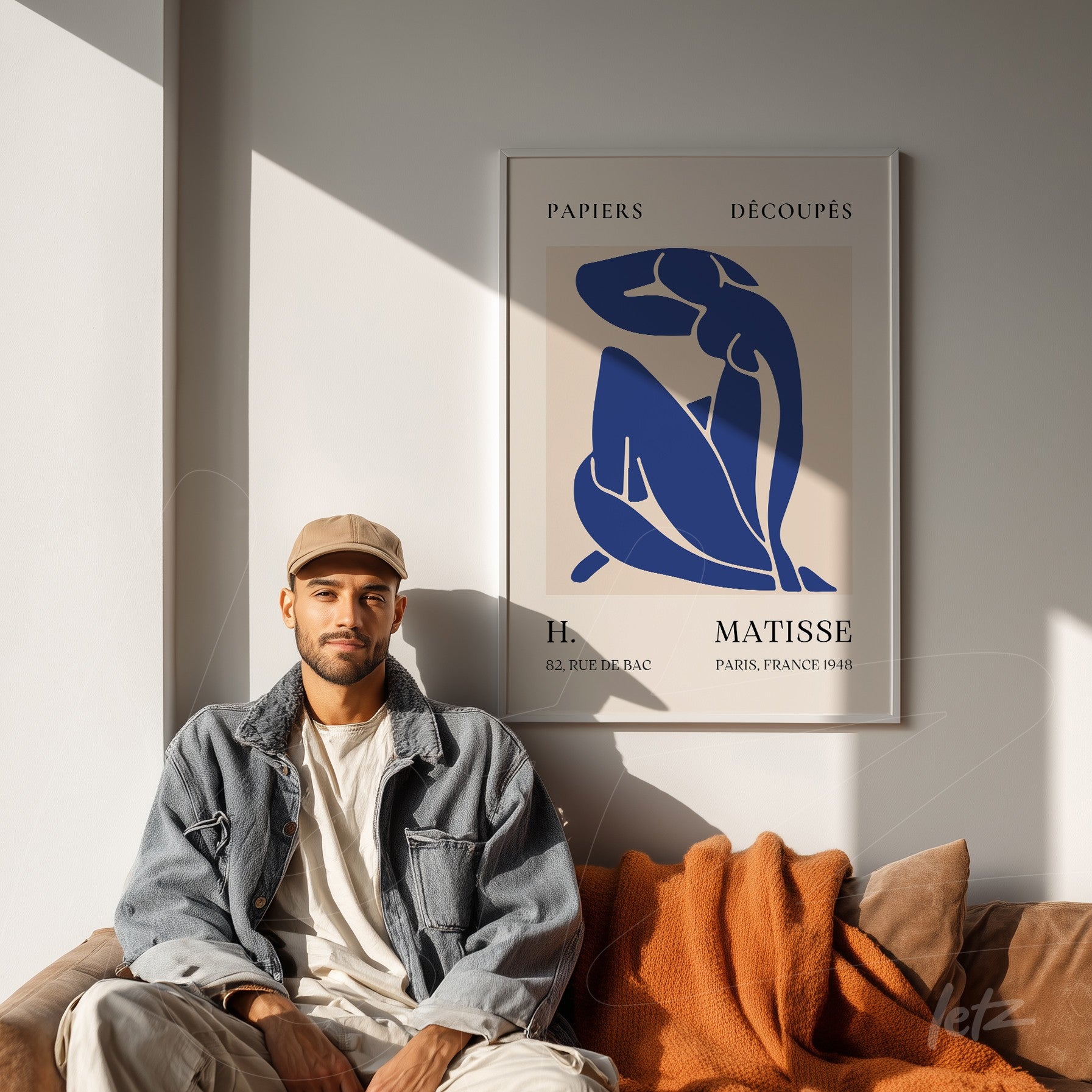 quadro decorativo com arte de Henri Matisse em moldura branca, exibido sobre parede clara com uma pessoa sentada em sofá