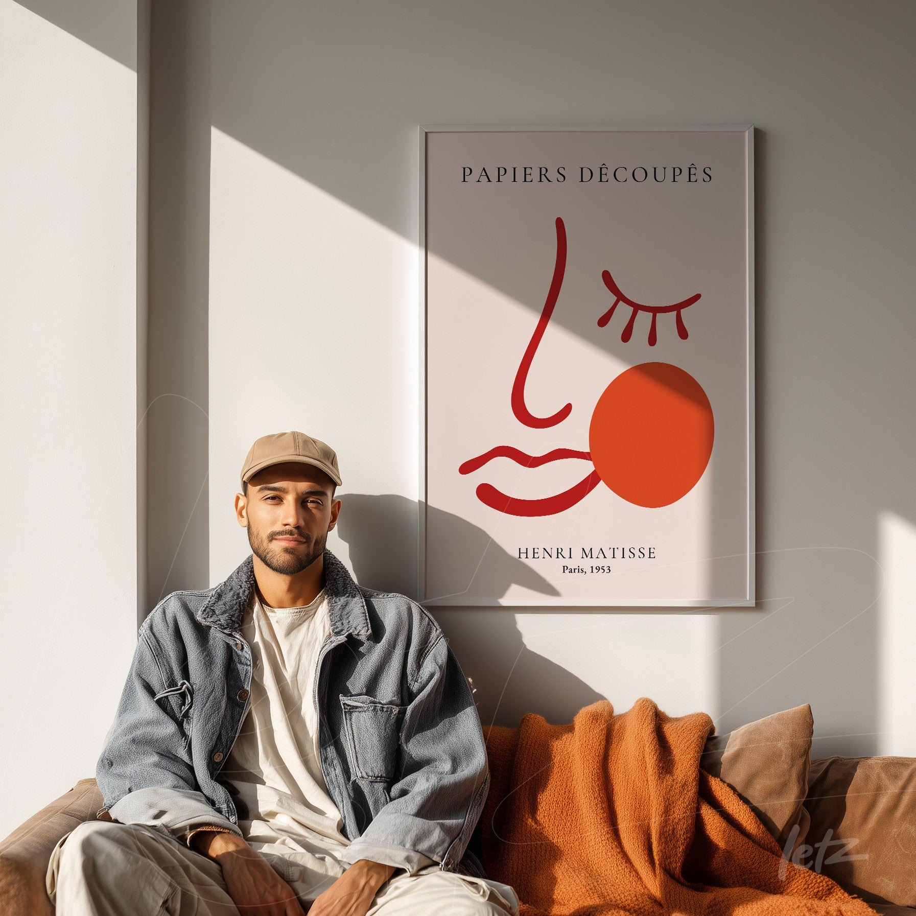 quadro decorativo com arte moderna de Henri Matisse em moldura clara, exibido sobre parede branca com pessoa sentada no sofá