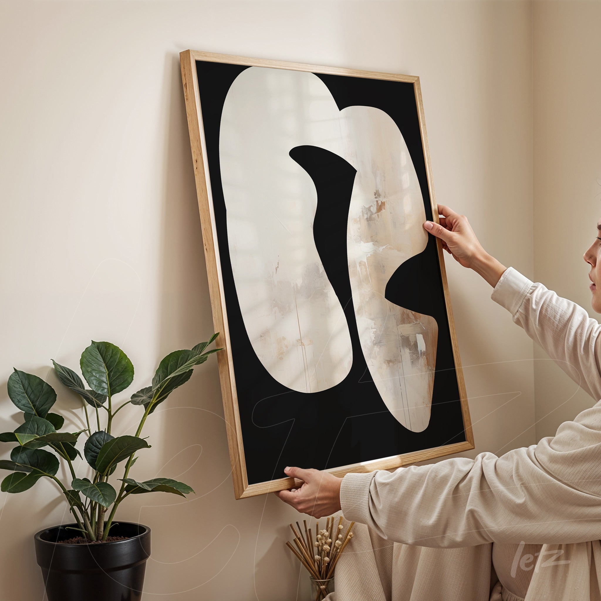 quadro abstrato com formas orgânicas em fundo preto, segurado por uma pessoa em ambiente claro com planta ao fundo